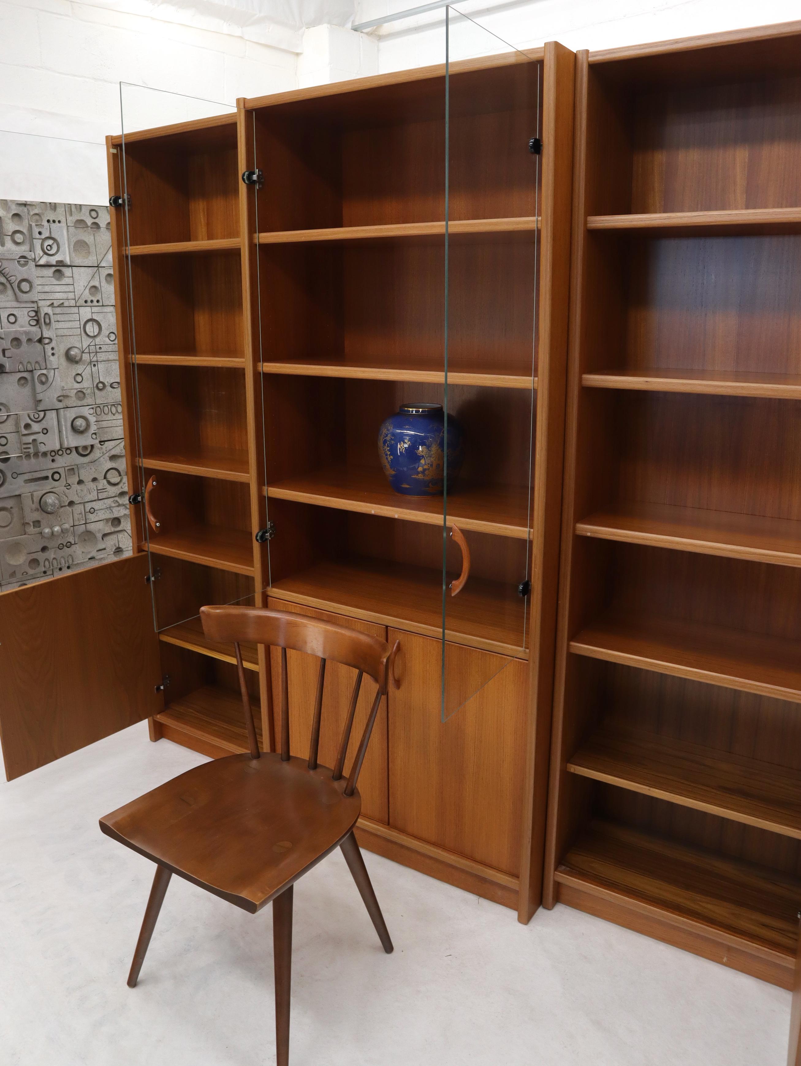 Danish modern teak wall unit vitrine consisting of three individual cabinets with adjustable shelves glass doors compartments.