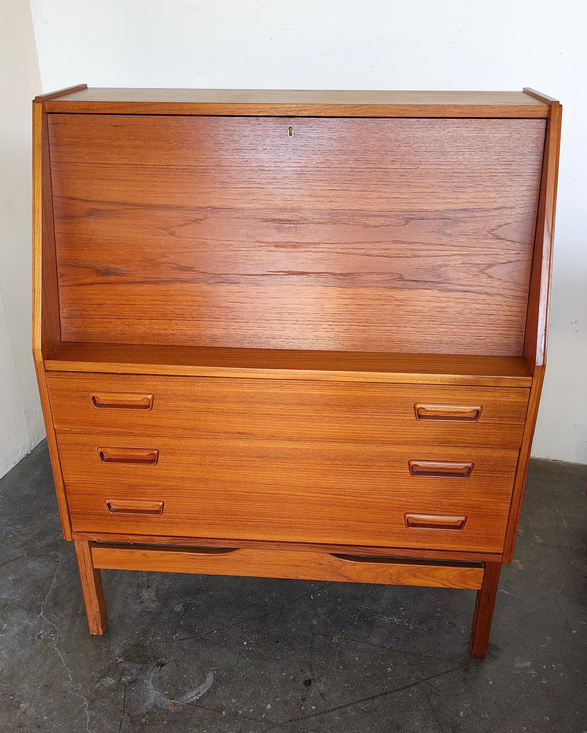 Drop-down teak secretary desk with three drawers by Dyrlund. Beautiful recessed solid teak handles, dovetail joinery and key pull for opening up the desk. Top opens up to envelope cubbies and two small sundry drawers. Great overall condition, there