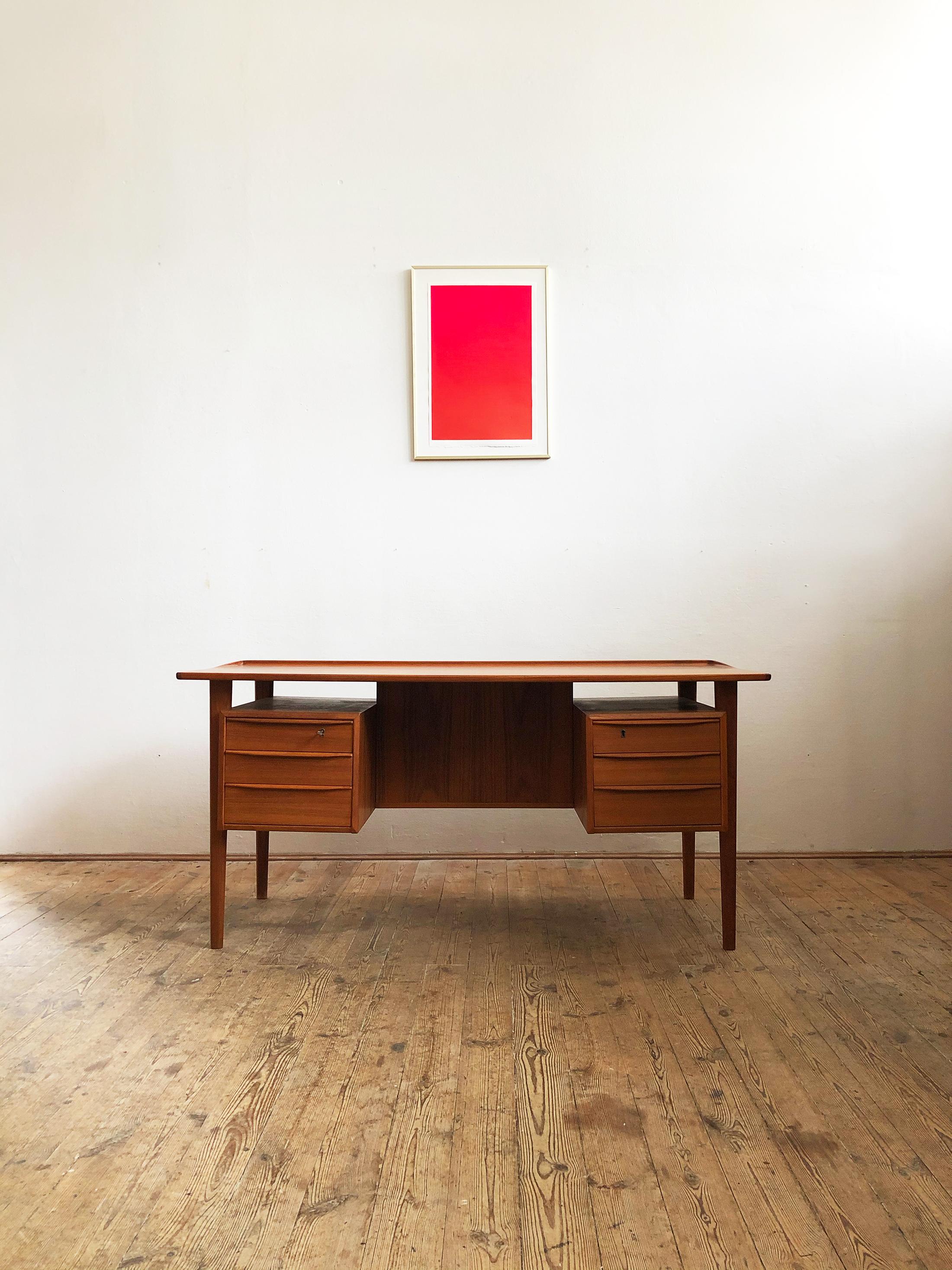 This free standing midcentury Danish writing desk was designed by Peter Løvig Nielsen for Løvig Dansk. The table is made of teak wood and features two sets of three drawers on each side and 2 storage compartments as well as a shelve on the tables