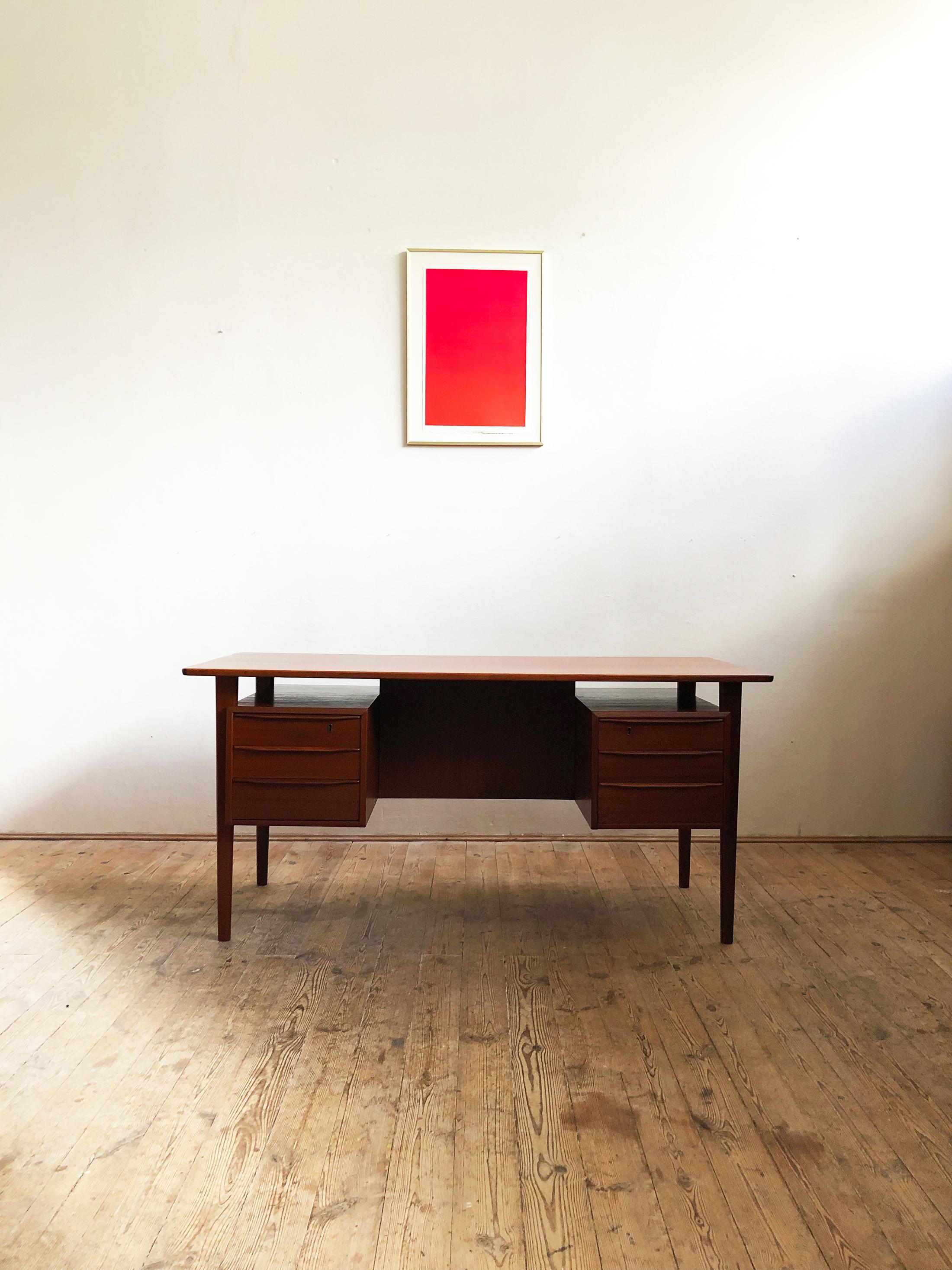 This free standing midcentury Danish writing desk was designed by Peter Løvig Nielsen for Løvig Dansk. The table is made of teak wood and features two sets of three drawers on each side and 2 storage compartments and a shelve on the tables back