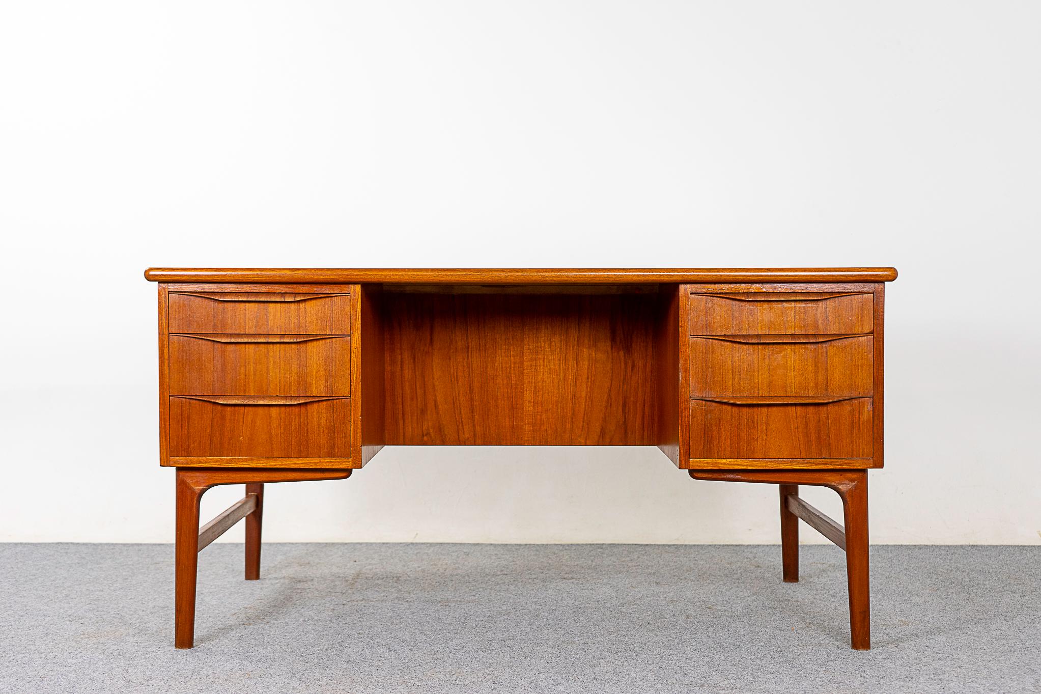 Danish Modern teak writing desk, circa 1960s. Writing desk finished on both sides, this desk can be placed in the center of a room and look fantastic on all sides. Hand formed curved drawer pulls offer ease of use when opening desk