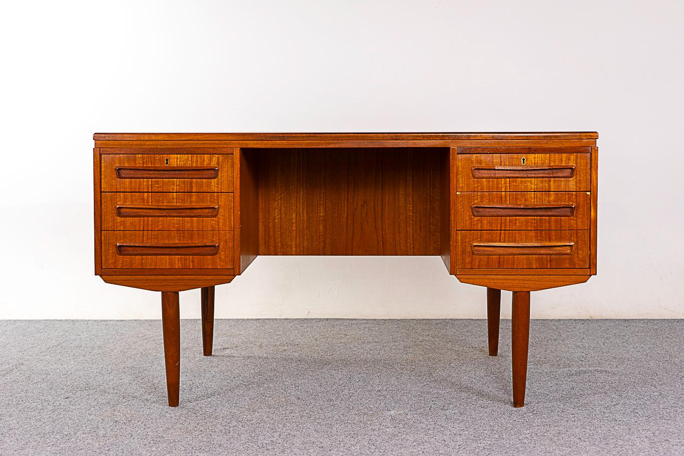 Teak mid-century Danish desk, circa 1960's. Finished on both sides, this beauty looks great from every angle! Sleek tapering legs, integrated low profile handles and ample storage. Sweet drop down compartment on the back side, maybe a mini