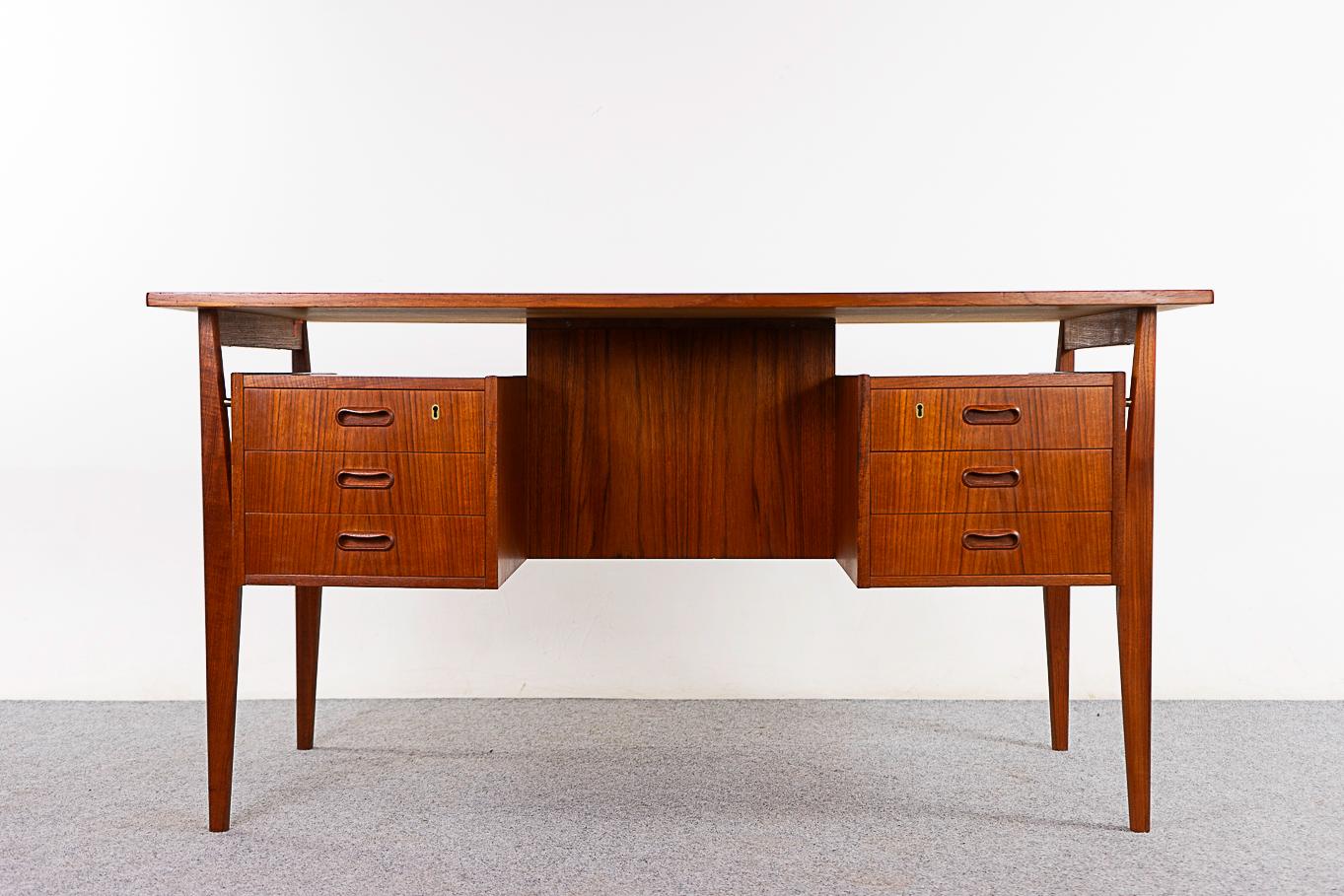 Teak mid-century desk, circa 1960's. Floating top with dual drawers and  finished back with shelf. Angular solid teak frame and beautifully bookmatched veneer throughout.

Unrestored item with option to purchase in restored condition for an