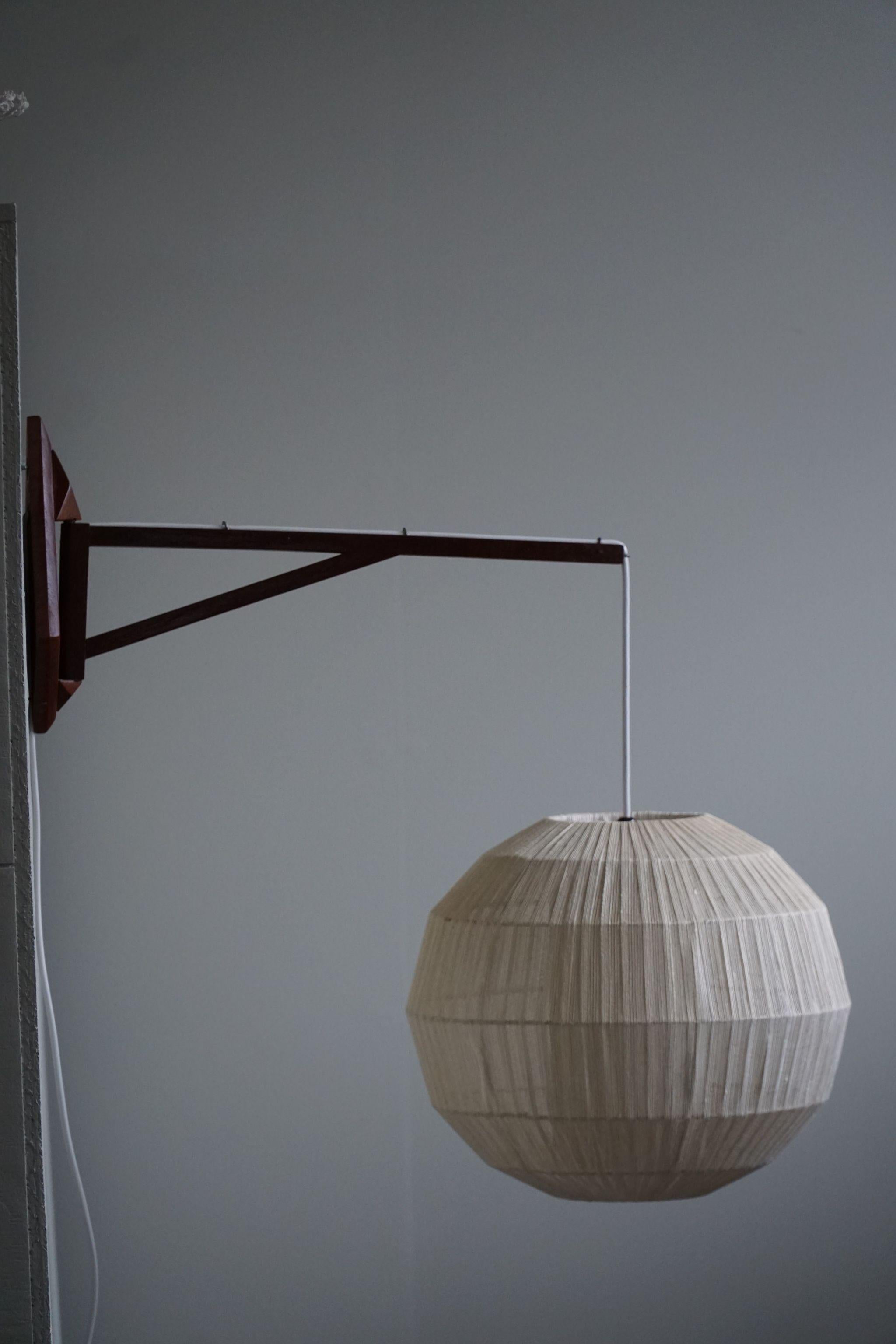 Intriguing swiveling wall lamp in teak & rope attributed to designer Ib Fabiansen for Fog & Mørup, Denmark. Made in the 1960s. 
This fine lamp gives a calm and cosy light to your home. A beautiful object that pairs well with many types of interior