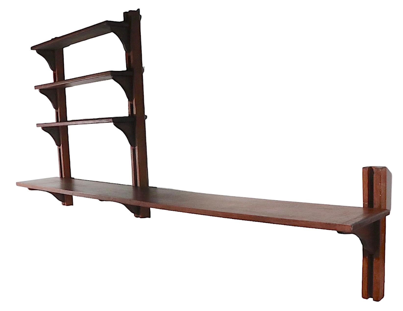 Danish Mid-Century Modern wall mount shelf, having four horizontal shelves, three vertical brackets, and nine support brackets. The lower shelf is 72.75 W x 10 D, the three upper shelves are 27.5 W x 10 D x Total H of unit 36 inches.
 This example