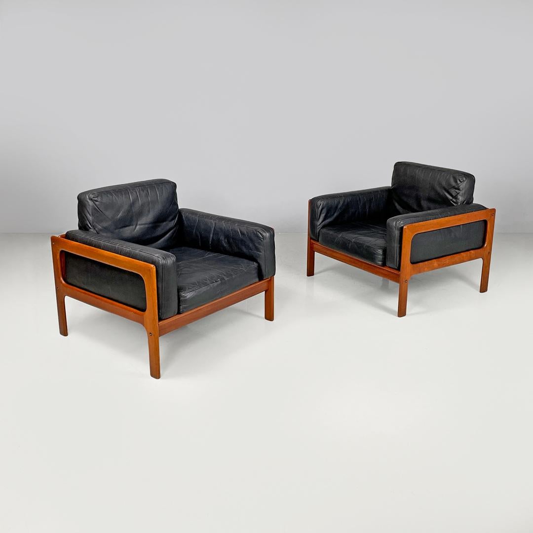 Danish mid-century modern wood and black leather armchairs, 1960s
Pair of black leather armchairs. The seats and backrests are made of rectangular padded cushions. The structure is made of wood with a rounded profile, and has two lateral armrests