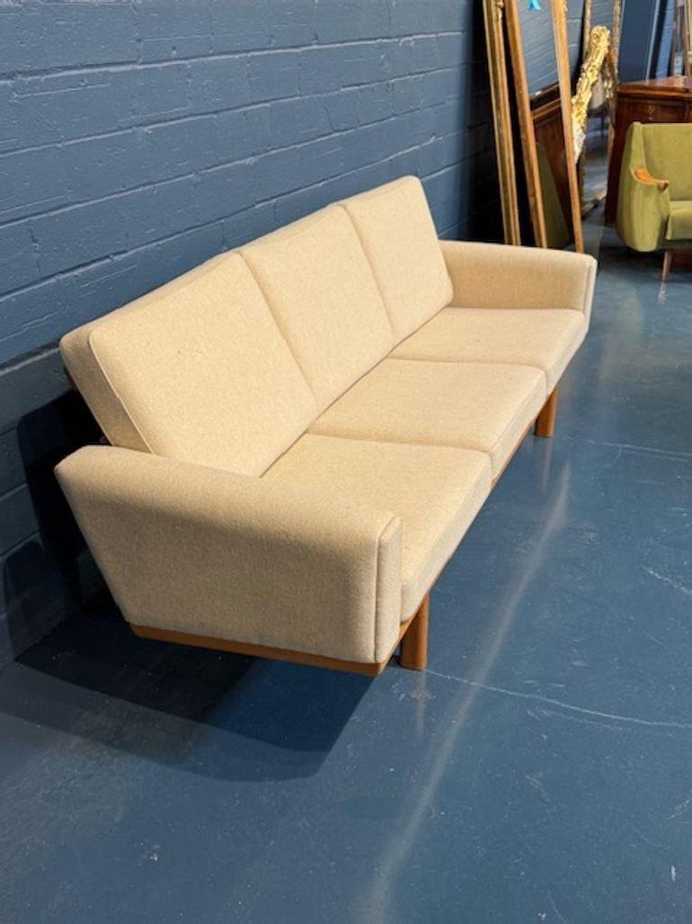 Eleva tu espacio vital con el Sofá danés de lana moderno de mediados de siglo, diseñado por el célebre Hans Wegner. Mezcla armoniosa de comodidad y estilo, este sofá es una pieza por excelencia para quienes aprecian la elegancia del diseño de