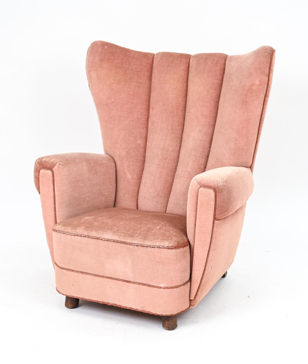 A gorgeous Danish early-mid 20th century wingback chair with a piped channel back design and rolled arms, in the manner of Mogens Lassen. c. 1940's, this chair highlights the transitional period of traditional design to Scandinavian modern design.
