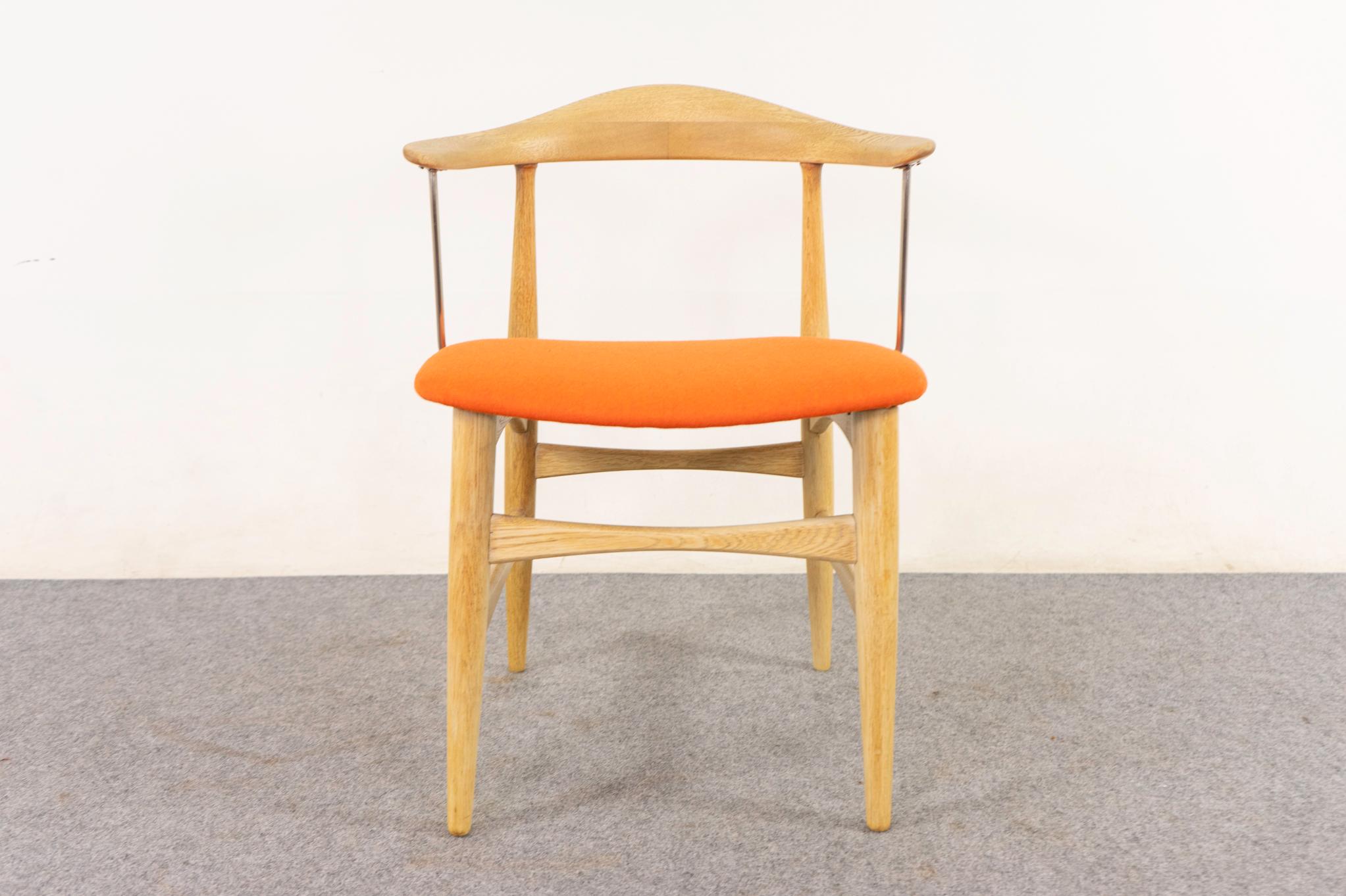 Oak Danish armchair, circa 1960's. Beautifully sculpted frame with bowtie cross supports, tapering legs and unique metal supports. New tangerine wool upholstery. Add a POP of color to your room!  