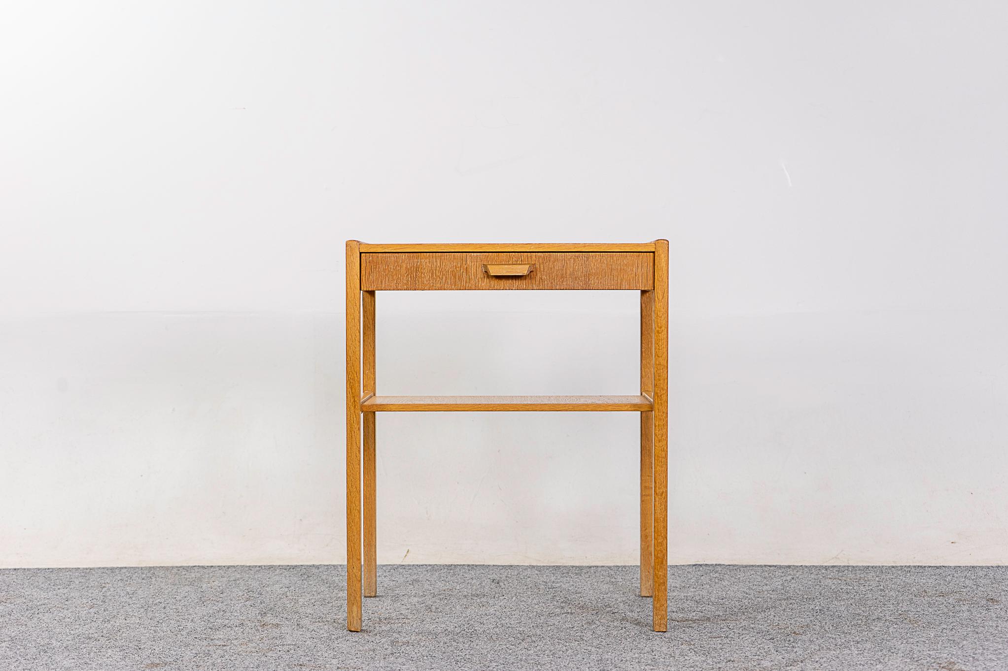Oak Danish bedside table, circa 1960s. Beautifully veneered case rests on slender, tapered, legs. Dovetailed drawer for storage of small items, open cubby is perfect for your favorite book! 

Unrestored item, some marks consistent with age.
