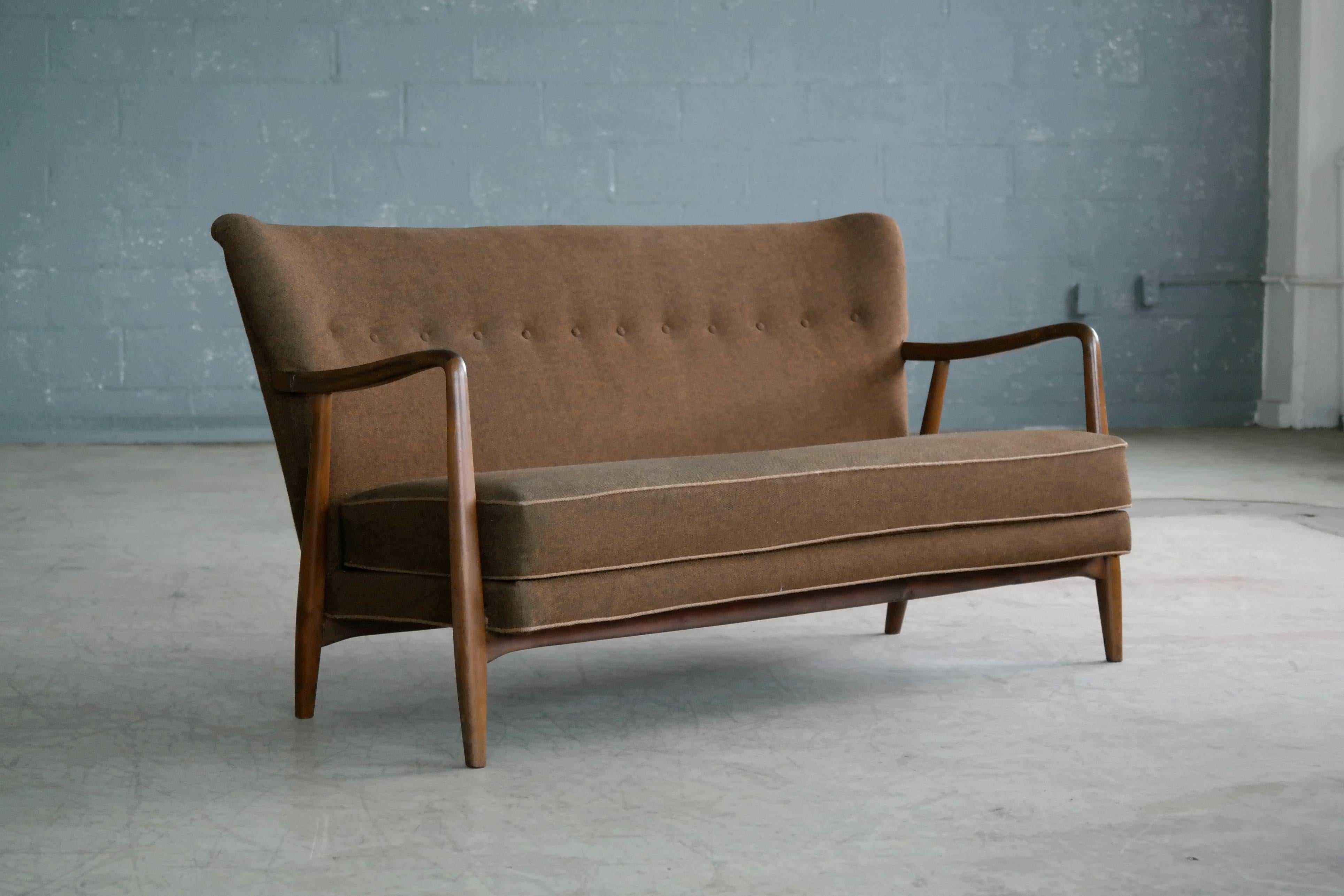 Elegant Danish midcentury settee in the style of Aksel Bender Madsen. We found the settee in Copenhagen but have not seen any identical settees over the years and we are unsure of the maker/designer. Very nicely carved beech wood frame with the
