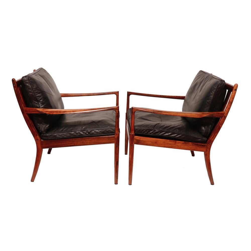 A Danish Mid-Century Pair of “Samso” Lounge Chairs Designed by the Danish Furniture Designer Ib Kofod-Larsen, 1960. Graceful and simple modern design of Rosewood outer frame and Beechwood seat frame with webbing and two original black leather