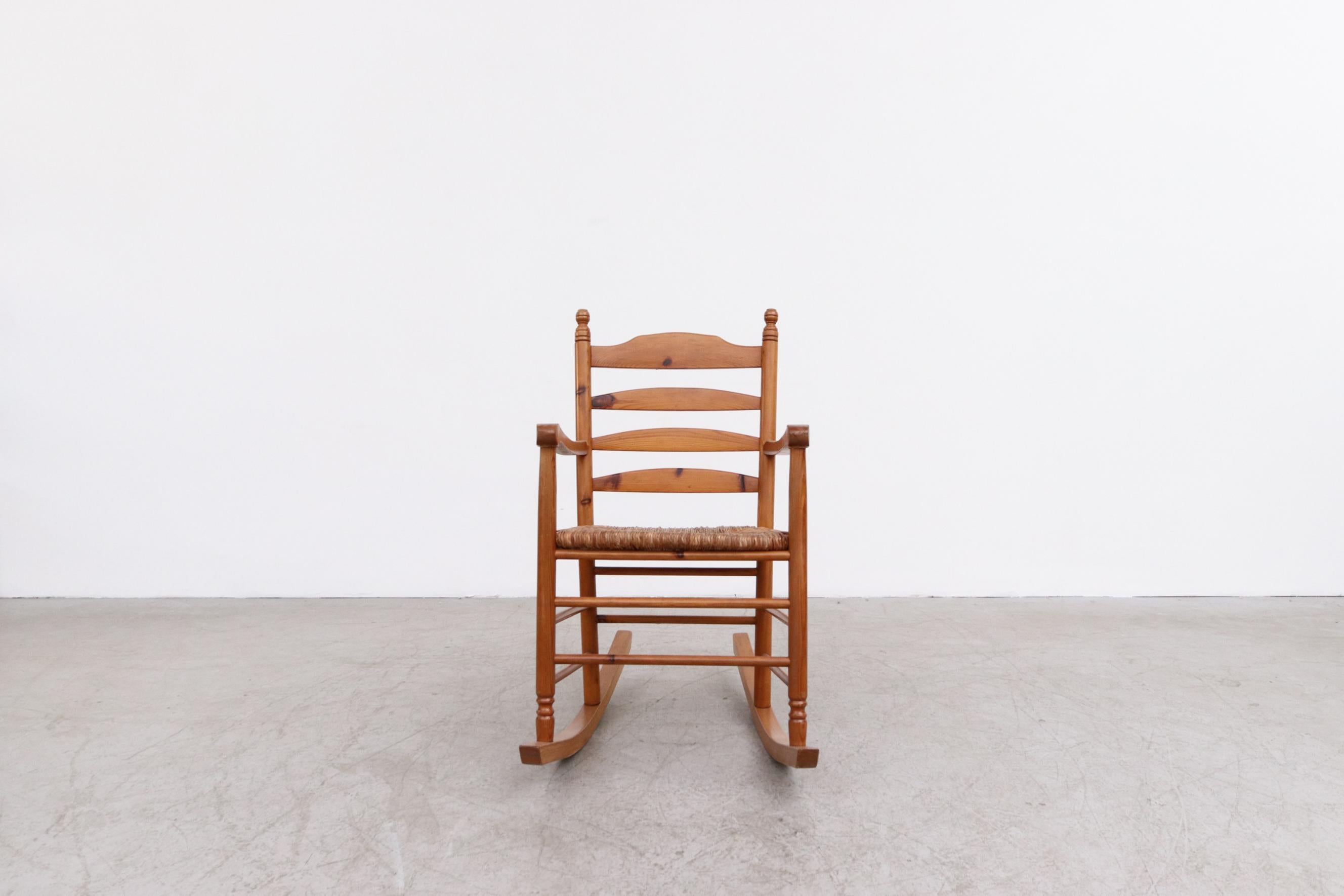 Danish mid-century pine and rush rocking chair inspired by Charlotte Perriand, Les Arc series. In good original condition with nice patina and visible wear. Condition is consistent with its age and use.