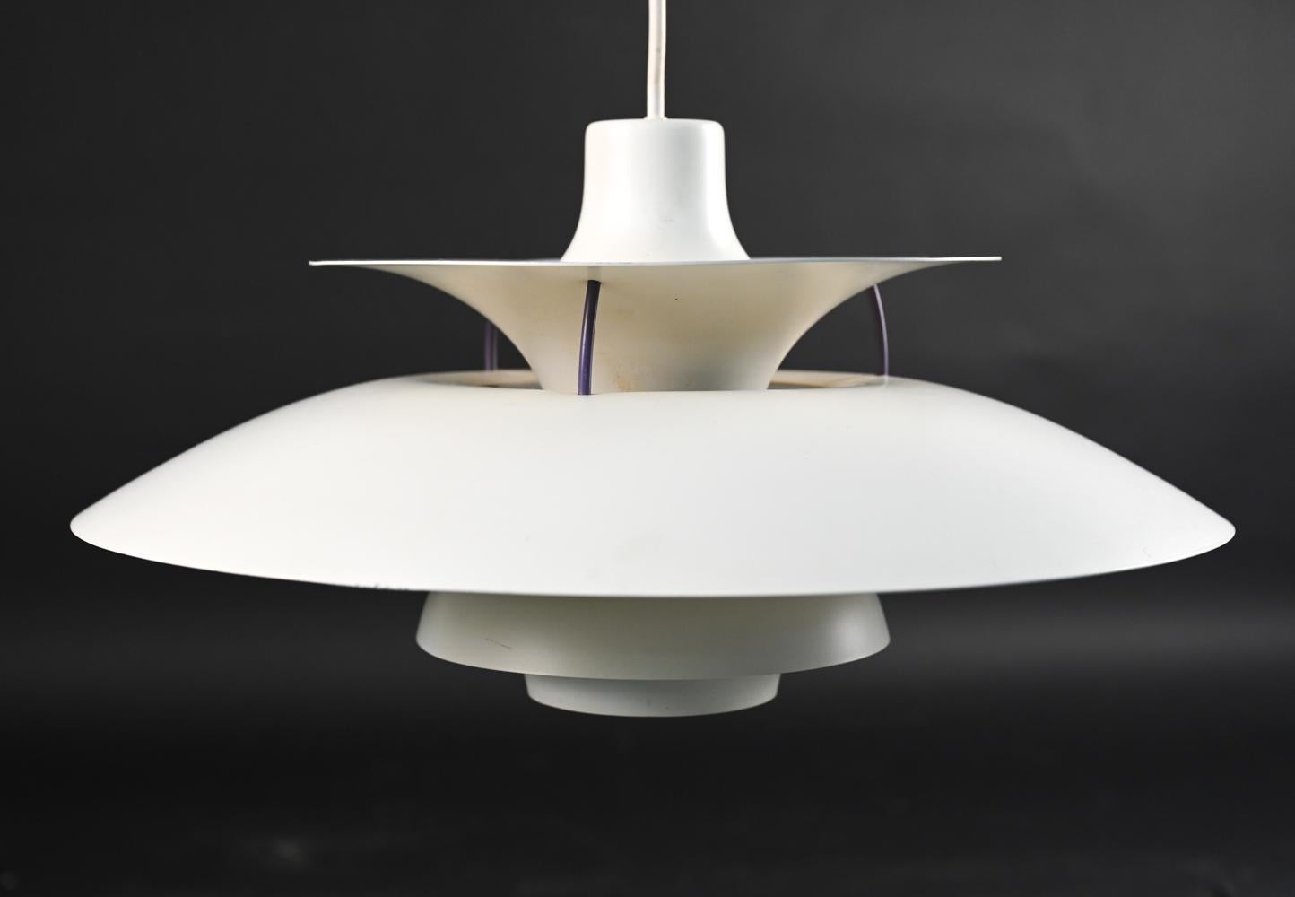 An iconic Danish design that is a mainstay of European homes, restaurants, and libraries, this mid-century modern pendant lamp, the PH5 Pendant Lamp, utilizes an ingenious system of shades and reflectors to produce a warm, welcoming glow. Designed