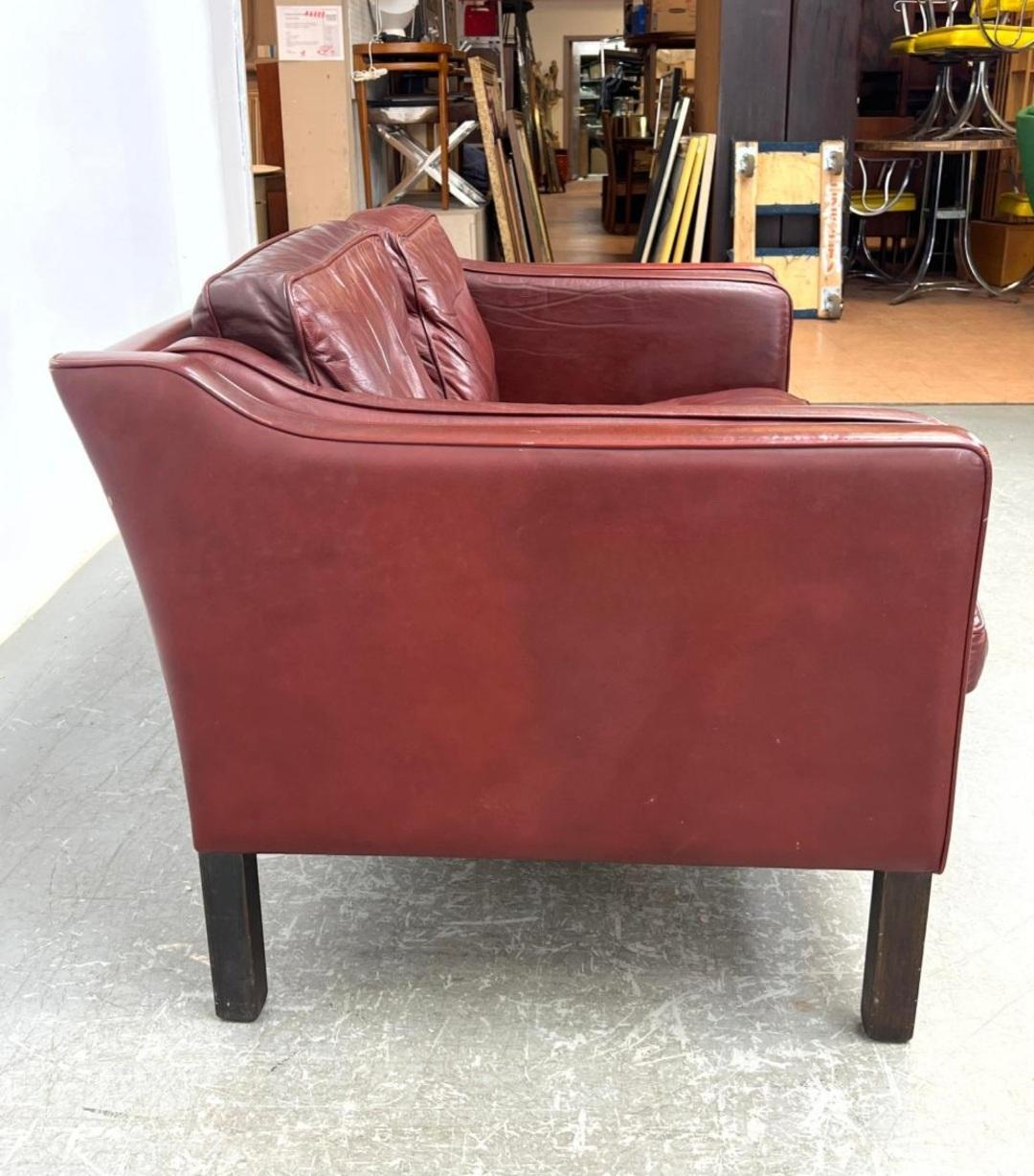 Luxurious leather loveseat with rich (rare) red color by Mogens Hansen. This loveseat features gently sloping track arms with austere and refined silhouettes. It's finished in supple leather with a soft rich patina that only time can create. 
 The