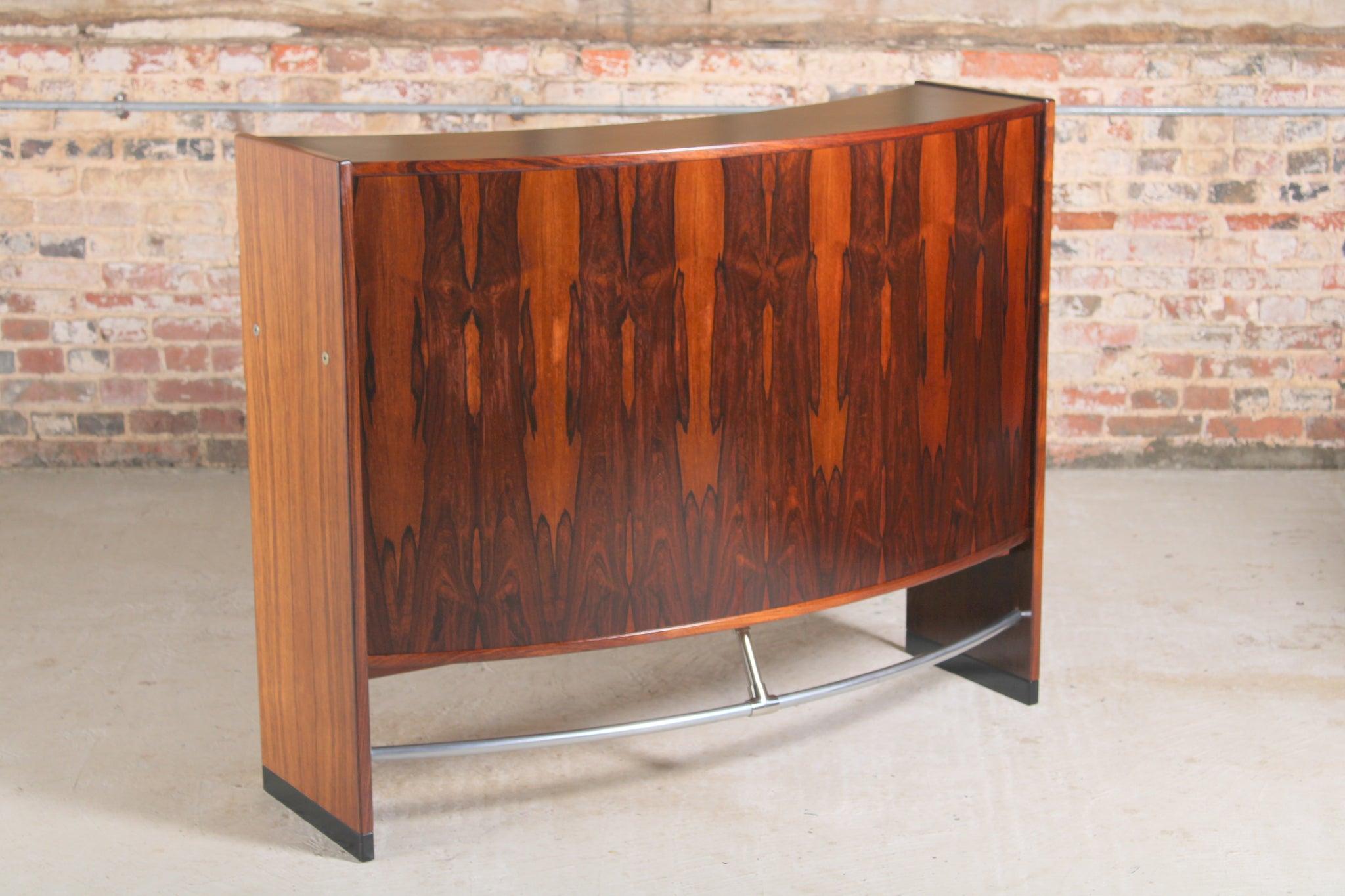 Danish Mid Century rosewood bar by Erik Buch for Dyrlund, circa 1960s. 2 sliding doors and 2 drawers with chrome handles. 7 bottle holders and a stainless steel footrest.

Dimension: W 130cm x H 105cm x D 55cm.

We offer international shipping,