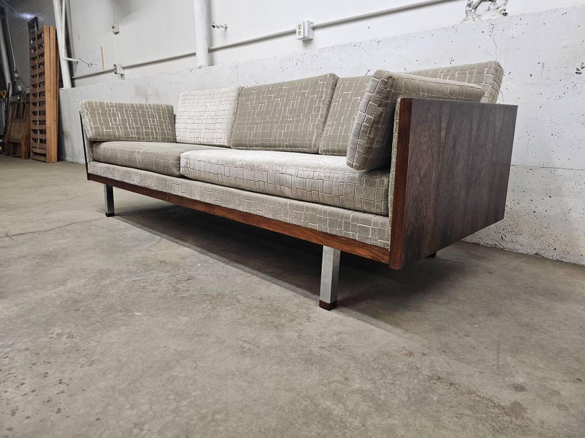 Made in Denmark by Jydsk Mobelvaerk it features beautiful bookmatched rosewood along the sides and back and it sits atop chrome legs which are accented by rosewood tips.

The boldly figured rosewood lends an organic quality to the otherwise clean