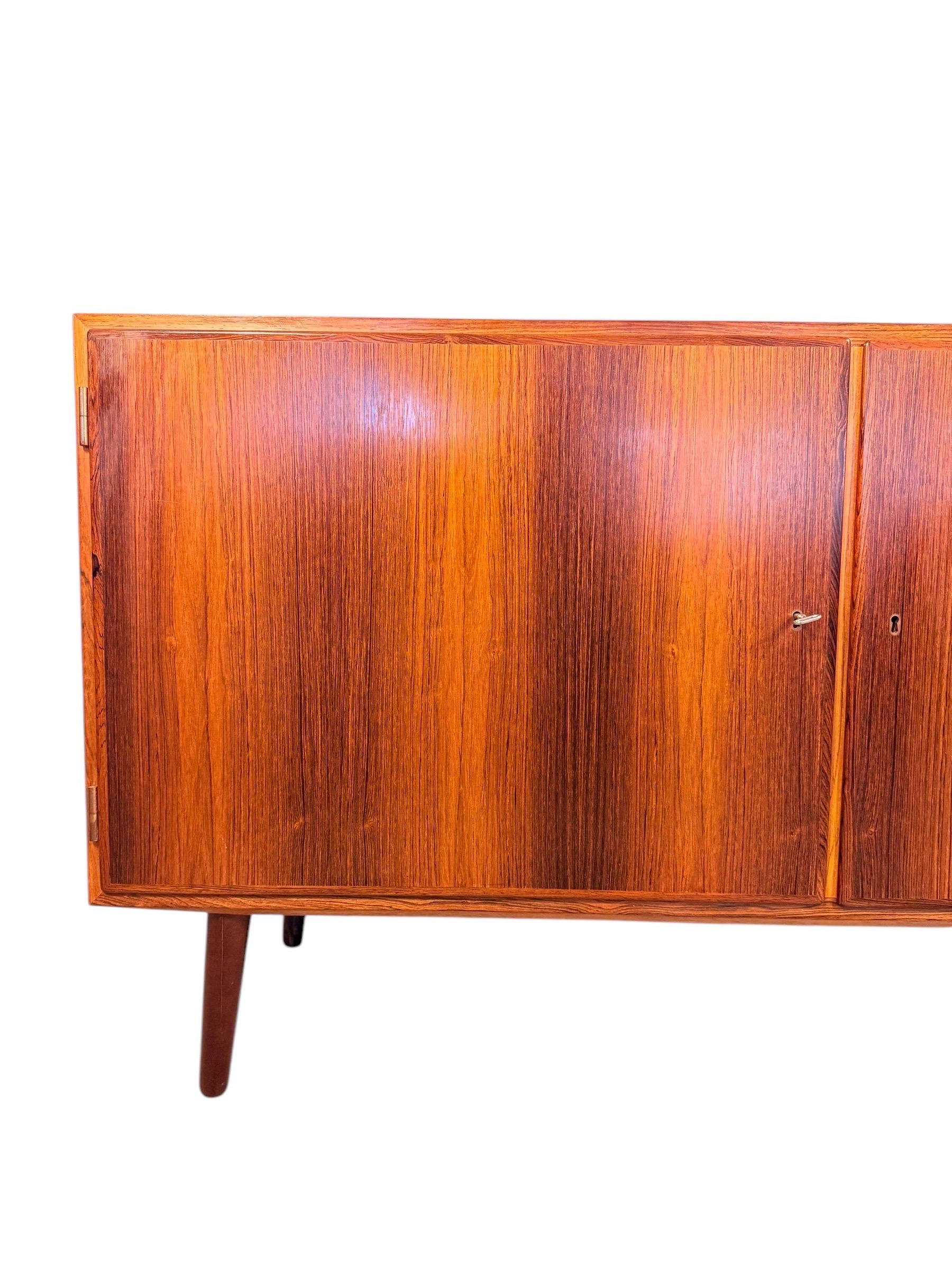 Una credenza in palissandro danese di ottima fattura disegnata da Carlo Jensen per Hundevad & Co. negli anni '60. Questo pezzo compatto ma funzionale misura 54,5