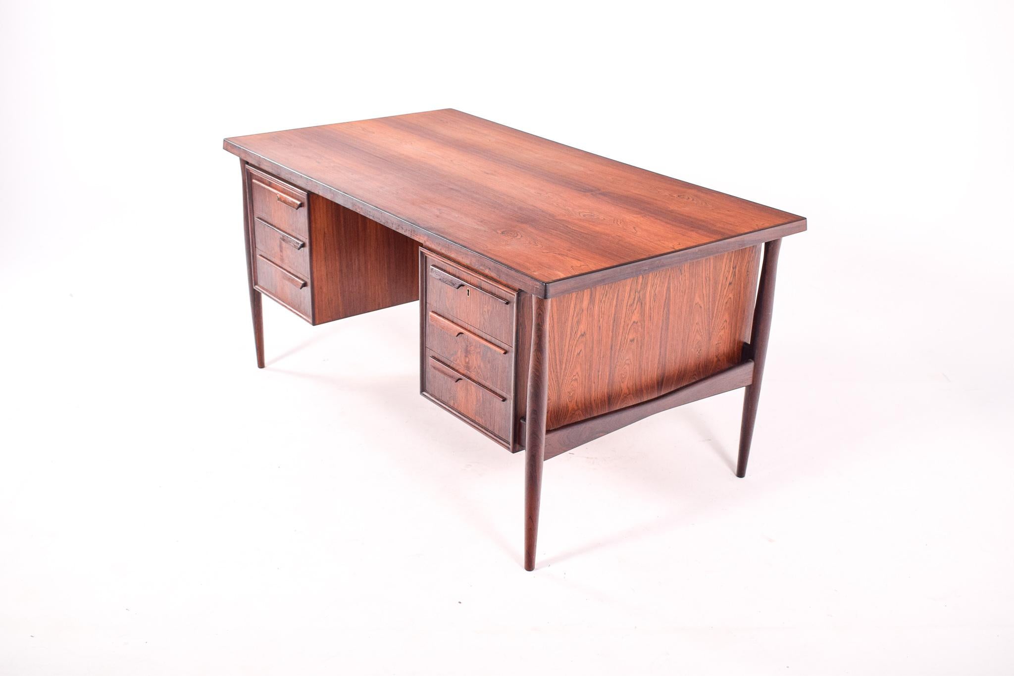 The beautifull rosewood color of this desk is exceptional. Striking rosewood grain throughout this piece. This desk designed by Arne Vodder for Sibast has three drawers either side and two cabinets at rear with solid rosewood pulls. Made during the