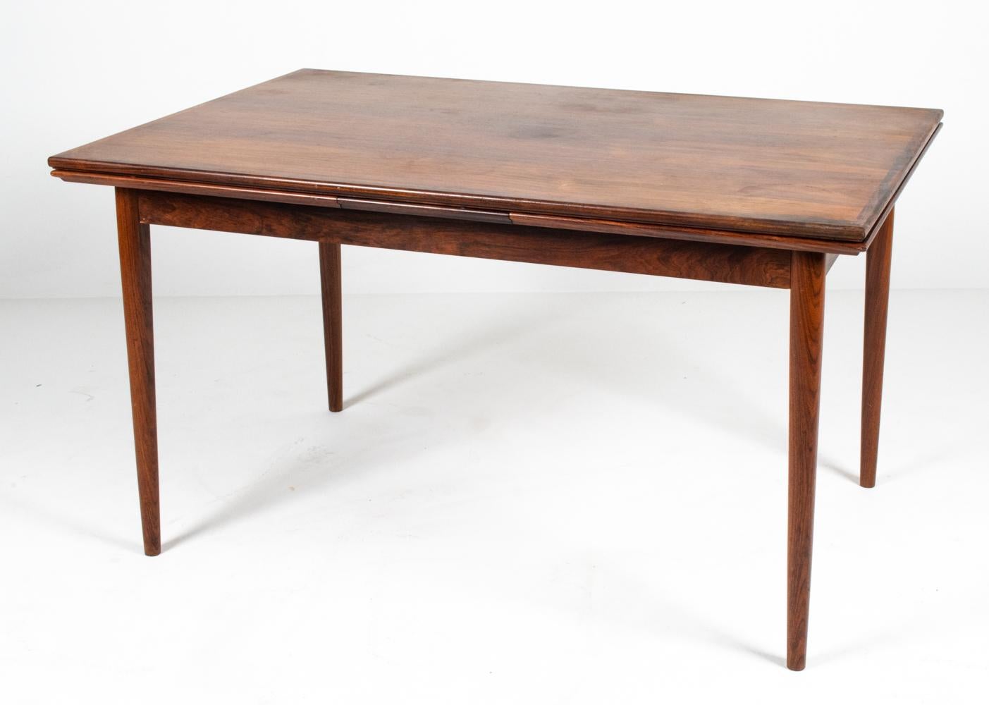Slim and stylish in its sleek proportions, this Danish mid-century extension dining table has a versatile appearance, well-suited to any modern or traditional interior alike. In typical 20th century Scandinavian Functionalist fashion, minimalist