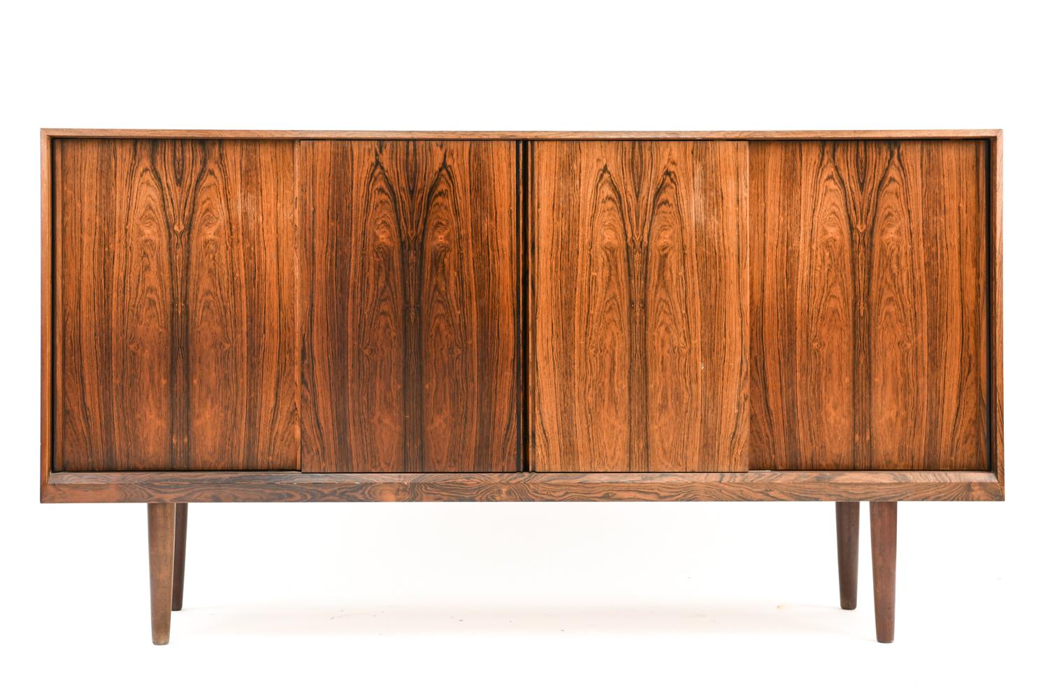 This Danish midcentury rosewood highboard was manufactured by Olholm, circa 1960s. Featuring adjustable interior shelves for optimal storage and book-matched rosewood veneered sliding cabinet doors for an attractive appearance.