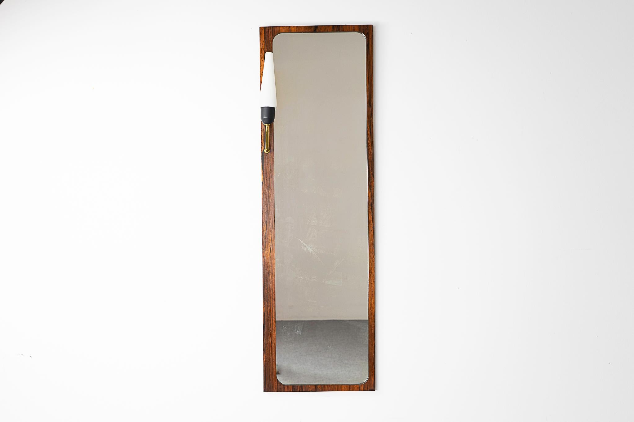 Rosewood Danish mirror with light, circa 1960's. Striking slim design with original frosted white glass fluted shade with brass arm, will need to be rewired. Date stamped October 3, 1957.

Please inquire for remote and international shipping rates.