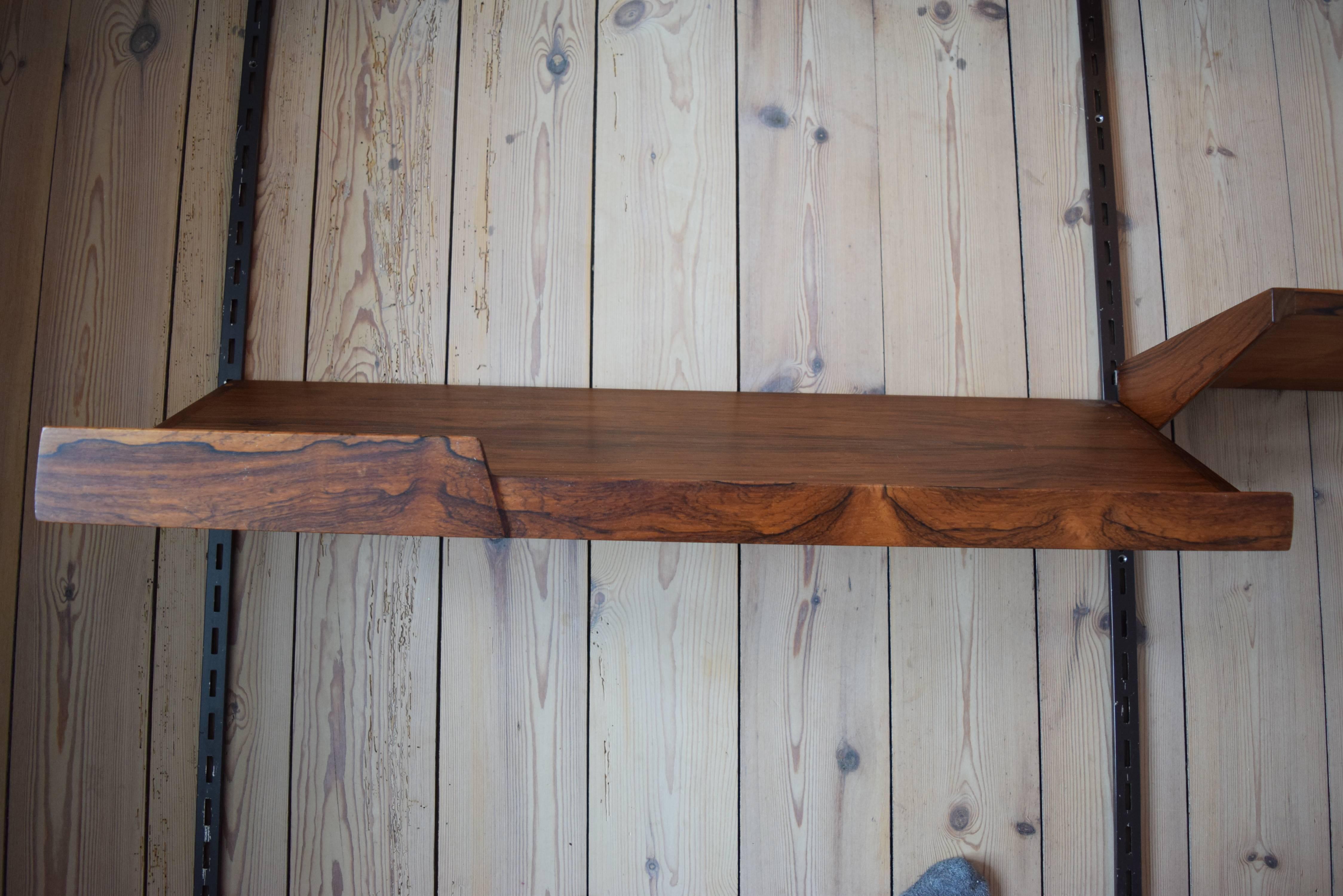 Set of eight rosewood shelves by Kai Kristiansen and manufactured by Feldballes Møbelfabrik, Denmark from the 1960s. This system comprises of six height adjustable small shelves, two desk top shelves and three metal hanging rails. This wall unit is