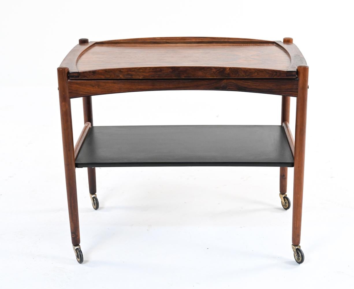 Keep the party going with this gorgeous Danish bar or serving cart in richly figured bookmatched rosewood, featuring a large removable tray top, black laminate bottom tier, and original brass casters.