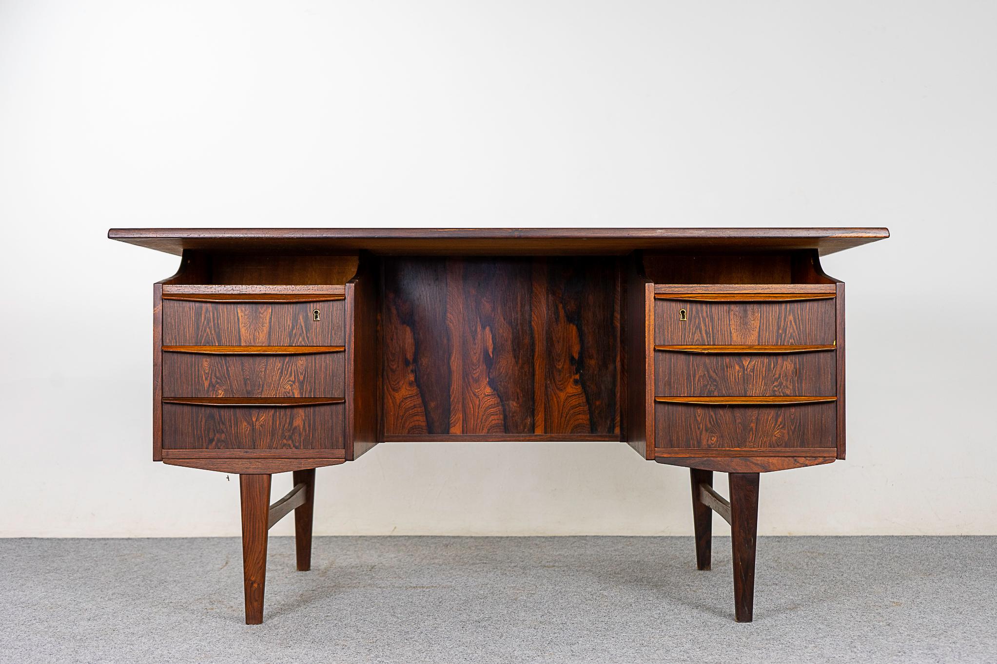 Rosewood Danish writing desk, circa 1960s. Finished on both sides, if centered in your room it will look fantastic from every angle. Hand formed solid wood drawer pulls, floating top, bowtie crossbars and ample storage!

Unrestored item, some marks