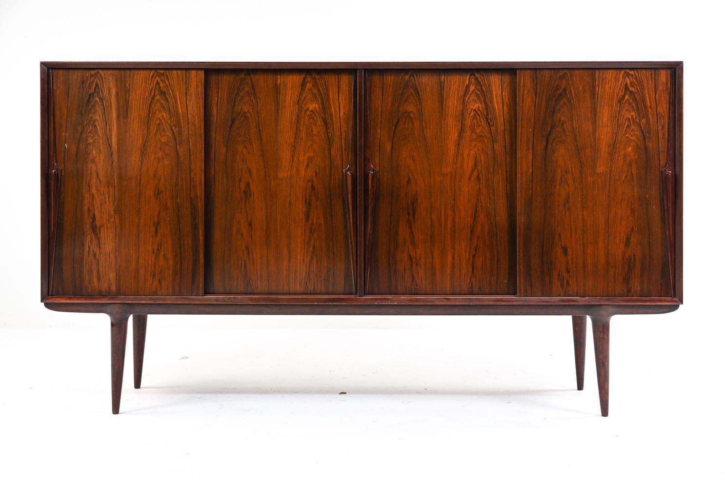 An exquisite and large buffet server or sideboard in rosewood, with sculptural handled sliding doors, ample storage shelves, and adjustable modular flatware trays. Unknown Danish maker, c. 1960's.