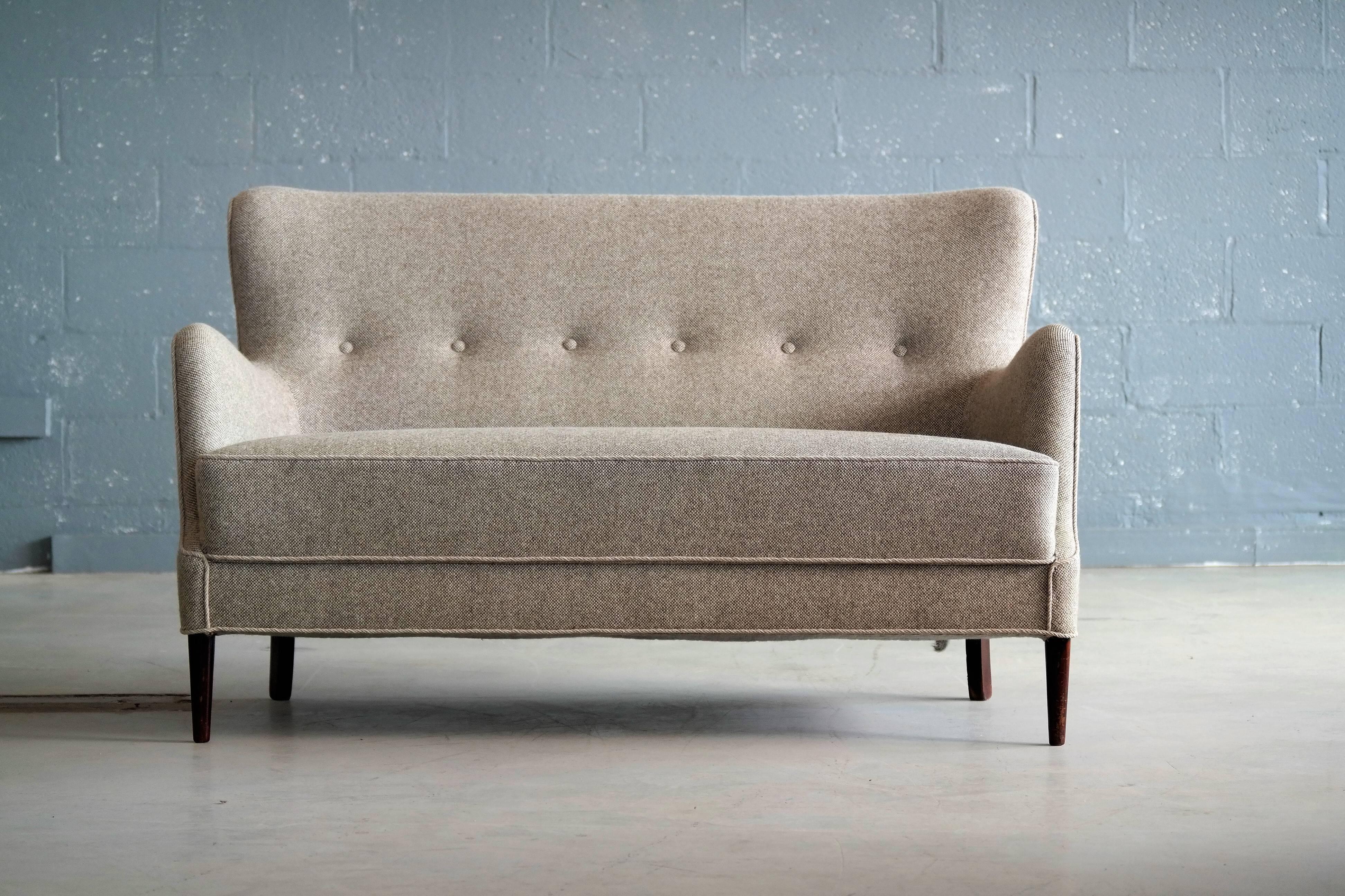 Elegant Danish or Swedish settee or loveseat from circa 1950s in the style of Carl Malmsten. Recently re-upholstered in a nice gray soft wool fabric. Sturdy and in overall excellent condition.

The sofa has clear design cues from both Frits