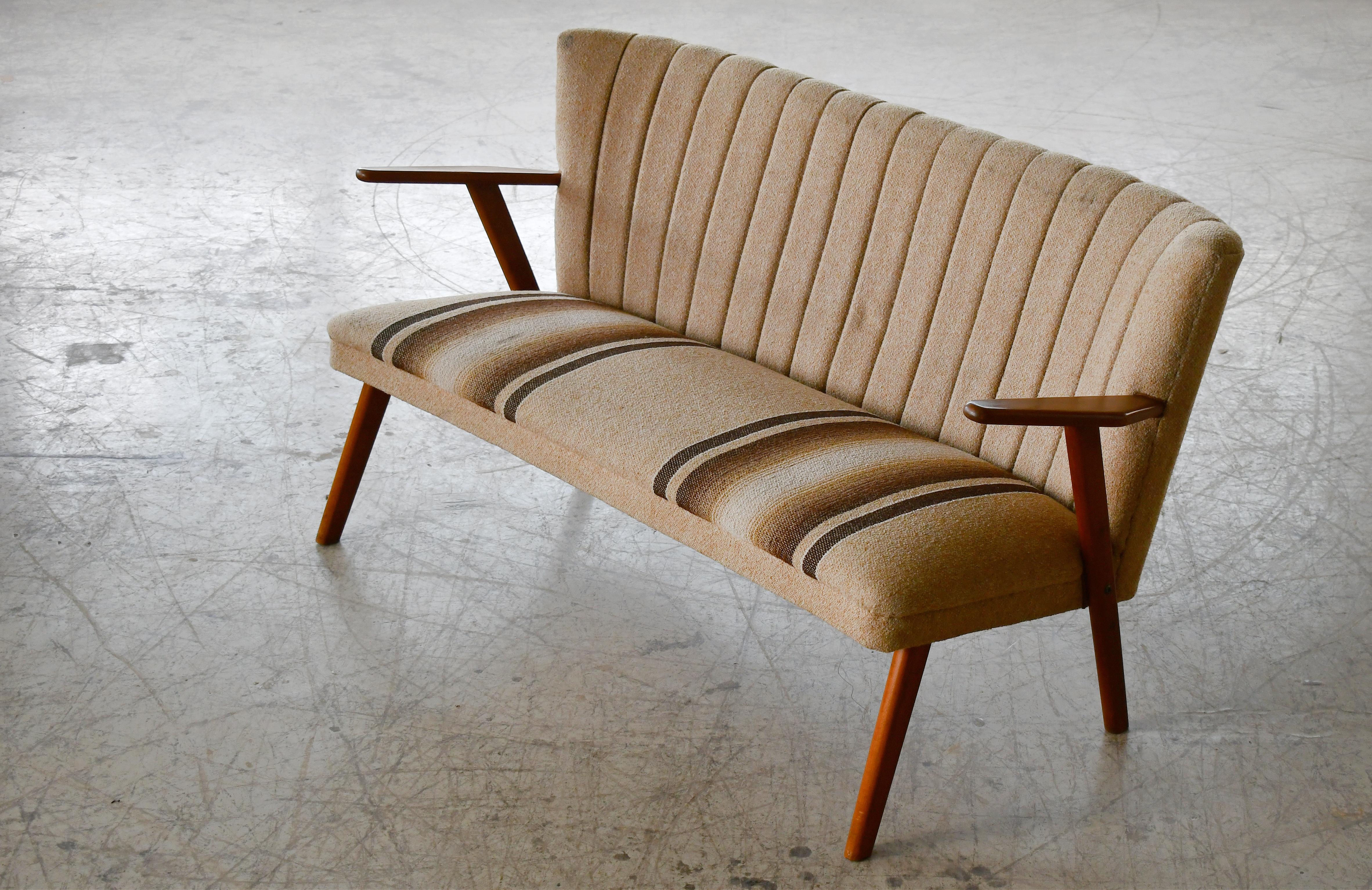 Precioso y encantador sofá o loveseat fabricado en Dinamarca, hacia 1950. El estilo es similar al de Kurt Olsen, pero se desconoce el diseñador y el fabricante de este canapé. Diseño ligero pero robusto y sólido, con patas de madera de haya y