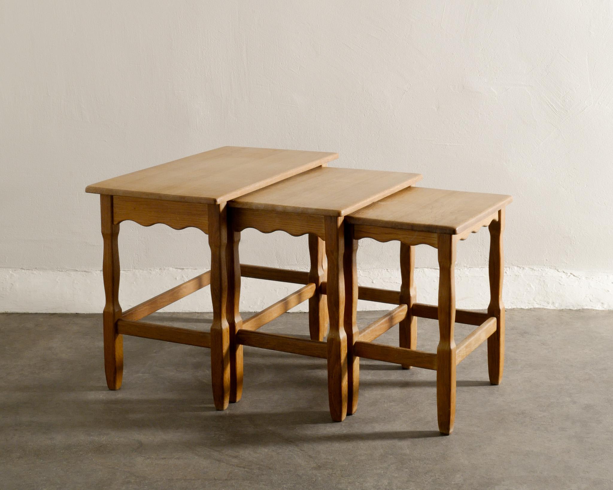 Rare set of mid century side stacking nesting tables in solid stained oak designed by Henning Kjærnulf produced in Denmark with some Jean Royère vibes. In good vintage condition with light patina from age and use. All tables are stable.