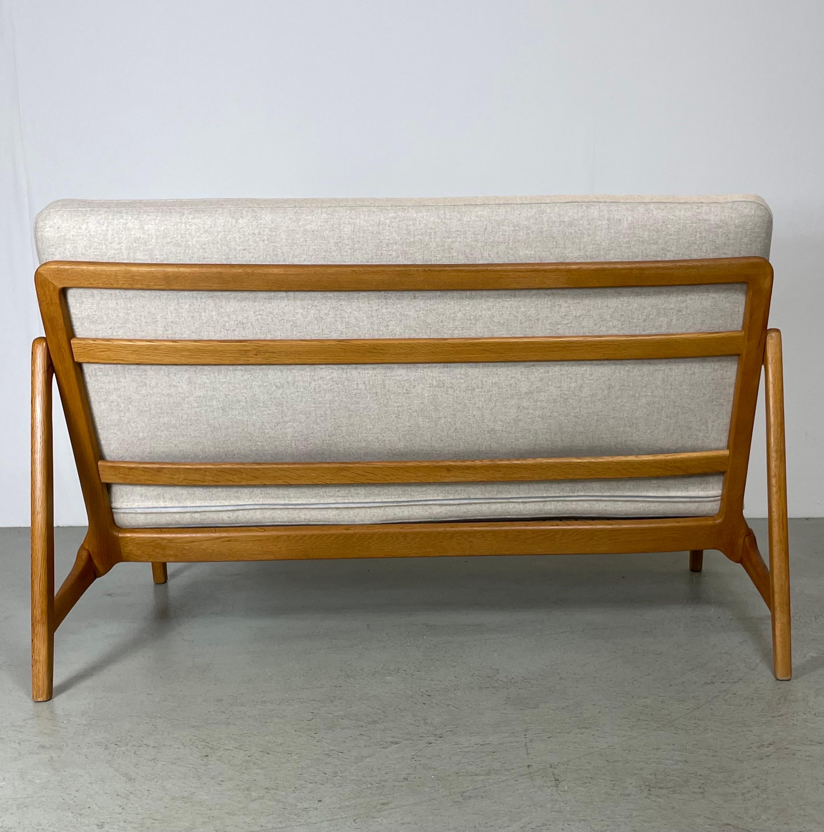 A comfortable 2-seater sofa designed by Danish architects Tove & Edward Kindt-Larson. Made in Denmark by France & Son during the 1950's. This model features a compact size with a wooden frame in oak and teak details on the armrests. It is fitted