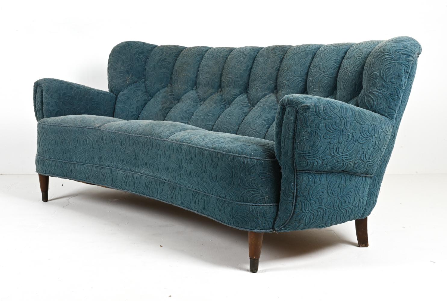 Journey into a world where design meets dream with this captivating Danish Mid-Century Sofa, channeling the evocative style of the legendary Flemming Lassen. A relic from the radiant 1940s, this piece gracefully straddles the line between art and