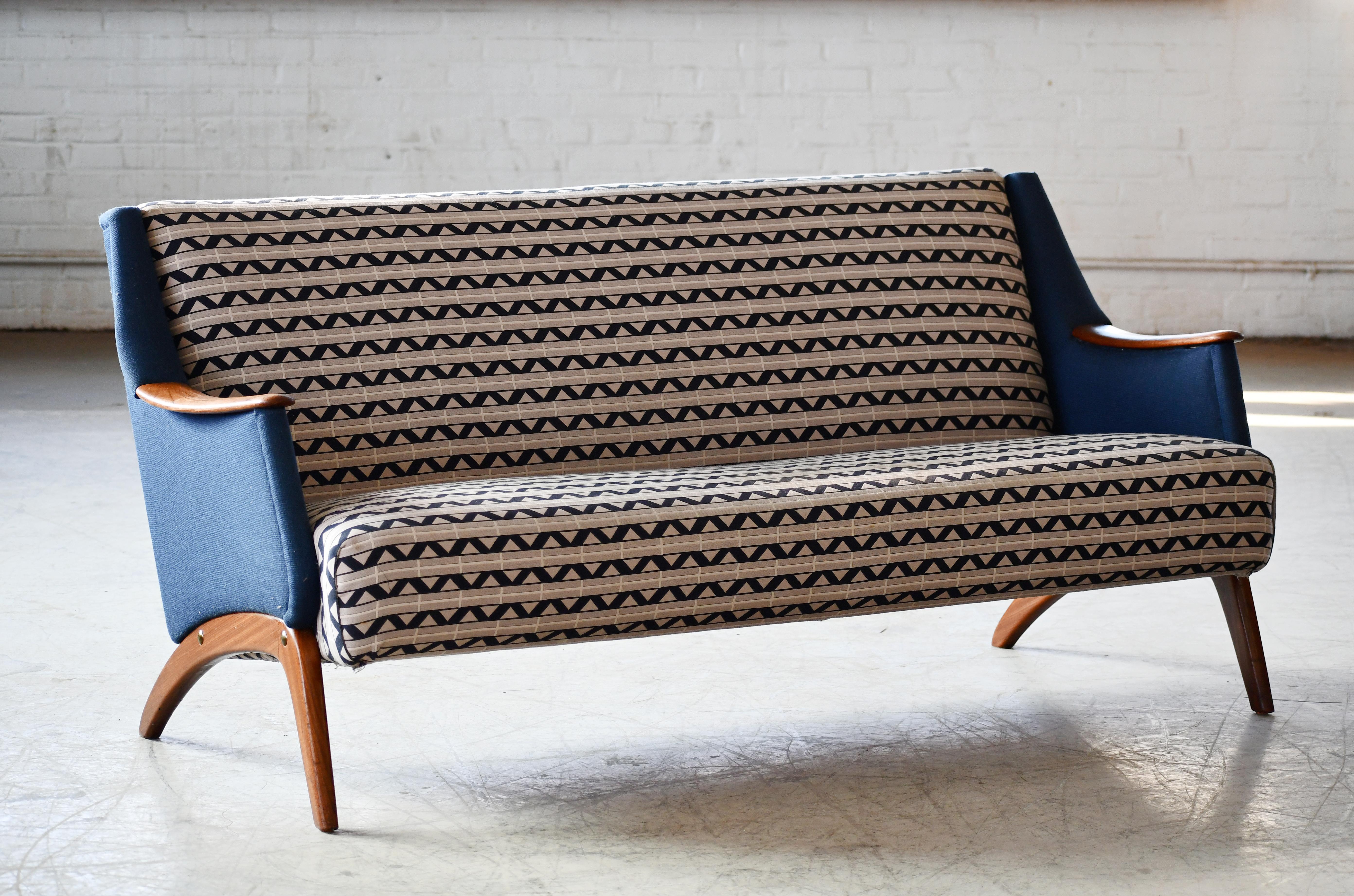Sehr klassisches und ultracooles dänisches Dreisitzsofa, das die 1950er Jahre verkörpert und an den Designstil von Kurt Olsen erinnert. Aufgebaut auf einem stabilen Buchenholzrahmen und auf massiven Teakholzbeinen mit Teakholzakzenten an den
