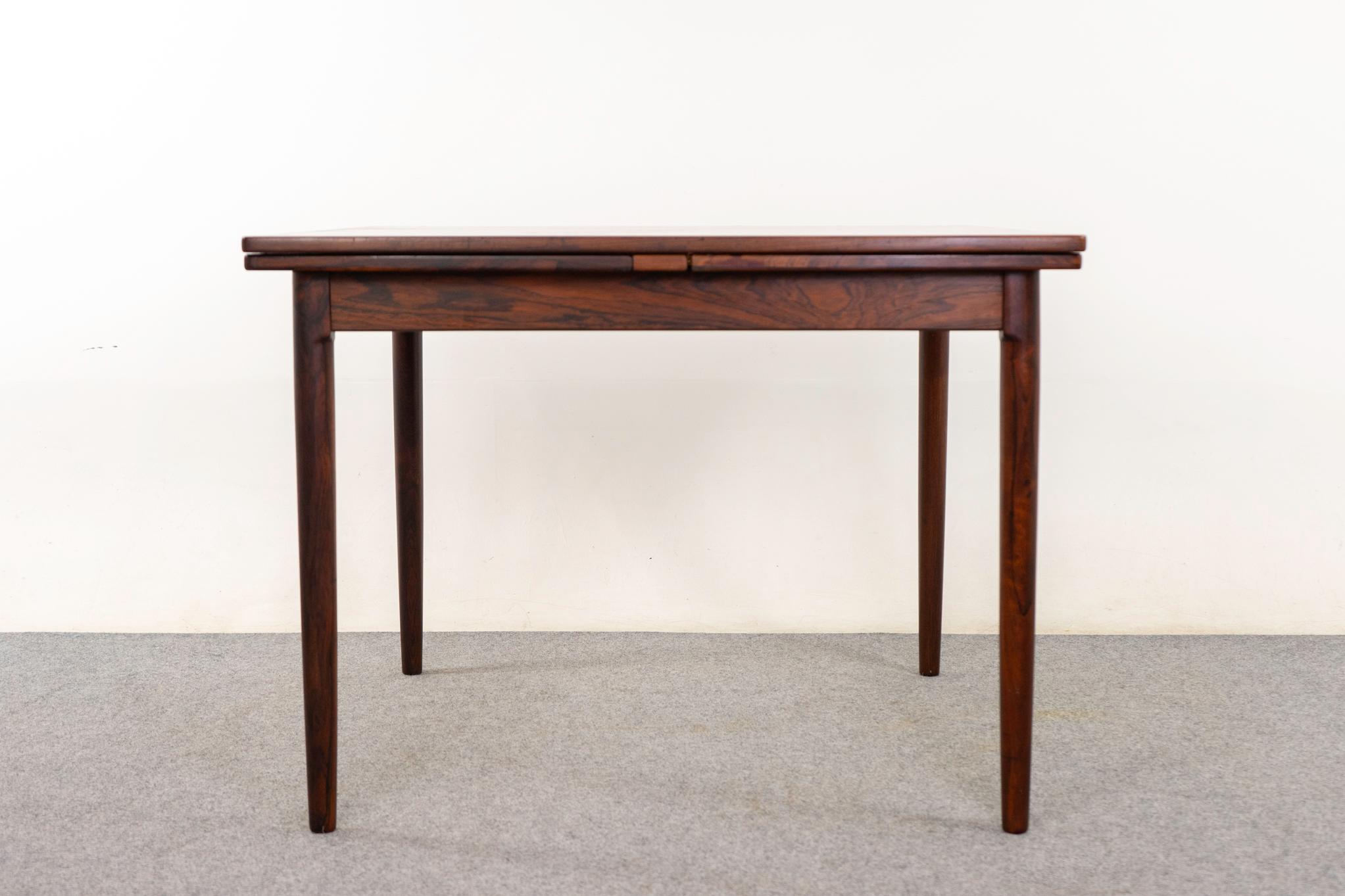 Rosewood Danish dining table, circa 1960's. Rare square! Solid wood edging with stunning book-matched veneer surface. Self-storing leaves slide out from the ends to extend the surface. Robust legs with an elegant taper! 

Unrestored item with option