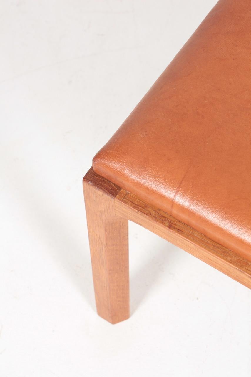 Stool in oak with seat in patinated leather. Designed by Kai Kristiansen for Aksel Kjærsgaard, made in Denmark, 1950s.
 