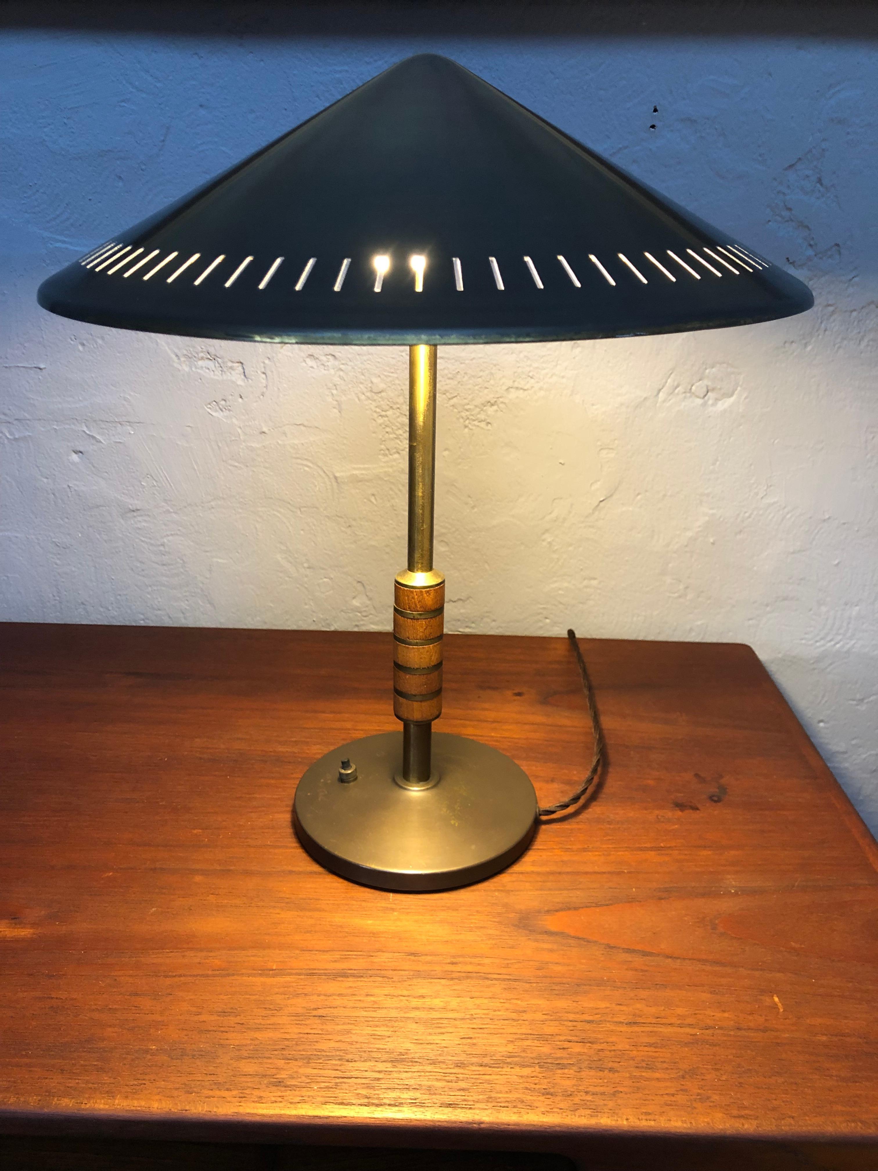 A classic Danish mid-century table lamp in brass and teak by Bent Karlby for Lyfa.
Mounted with a turned brass shade maintaining is original white paint. 
Brass and teak stem. 
Brass base with a brass on/off switch.
New black baize applied to the