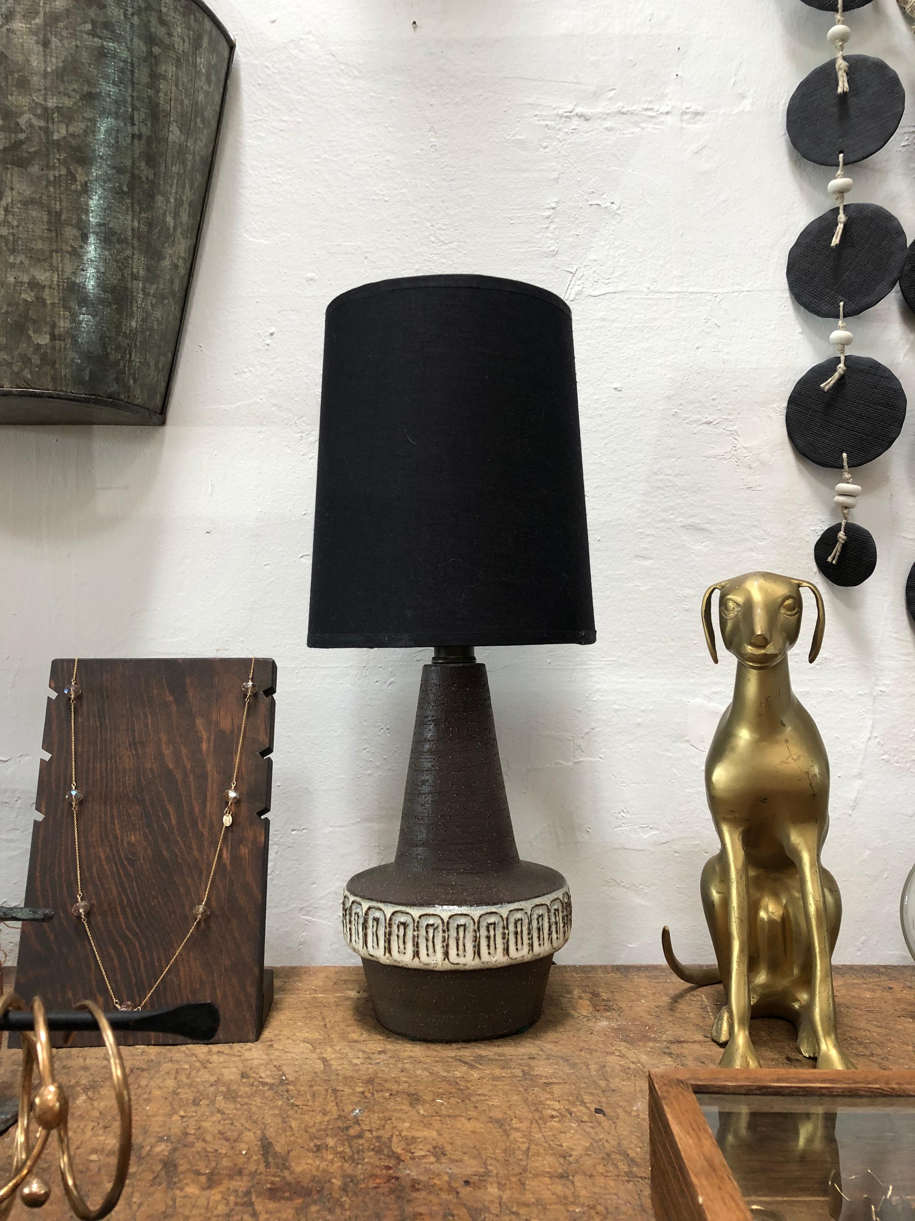 This vintage lamp is the perfect size for a small desk or entry way table. From the mid century, it features a beautifully simple geometric design and dark linen lamp shade.