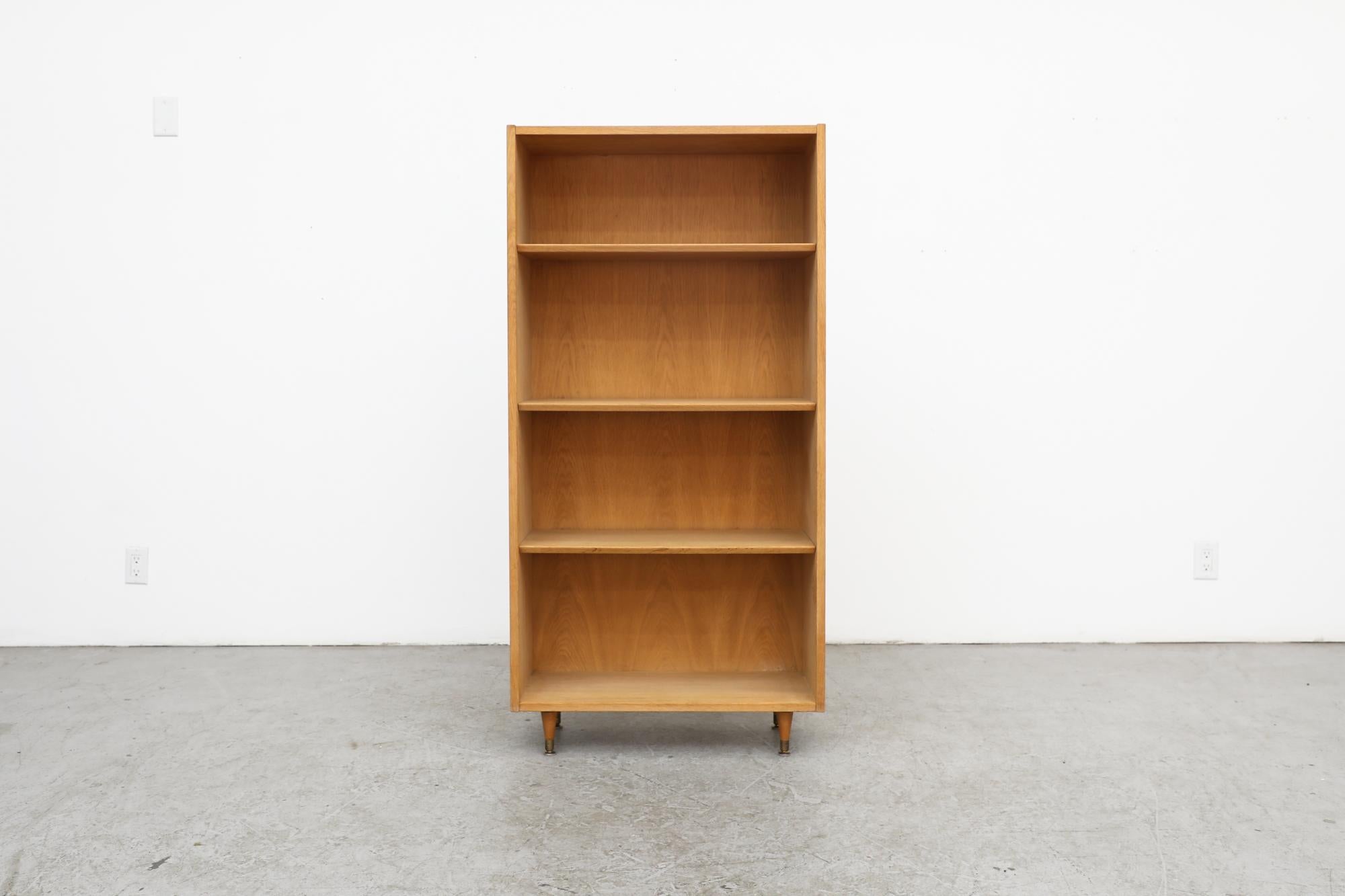 Tall Mid-Century Danish open bookcase in oak with tapered legs and adjustable height shelves. Legs may not be original to the unit. In otherwise original condition with visible wear, consistent with its age and use.