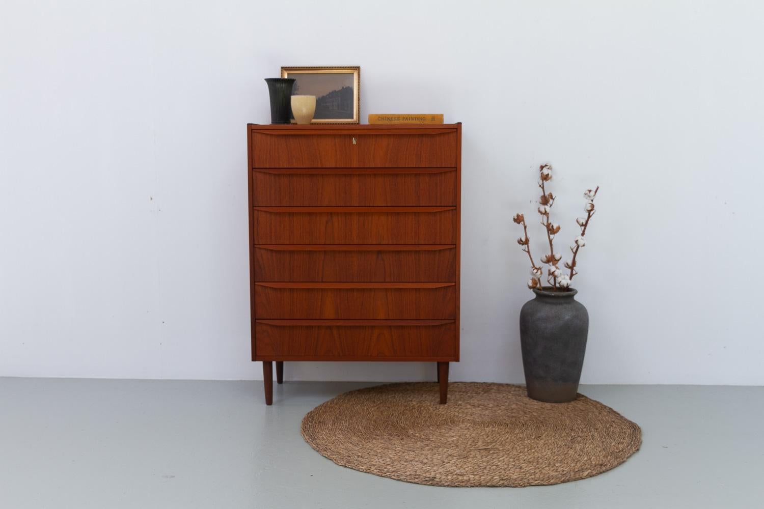 Danish Mid-Century Tall Teak Dresser, 1960s.

Very expressive Scandinavian Mid-Century Modern chest of drawers with six wide drawers. Long sleek pulls in solid teak on the drawer fronts. Top drawer with lock, key is included. 
Standing on four round