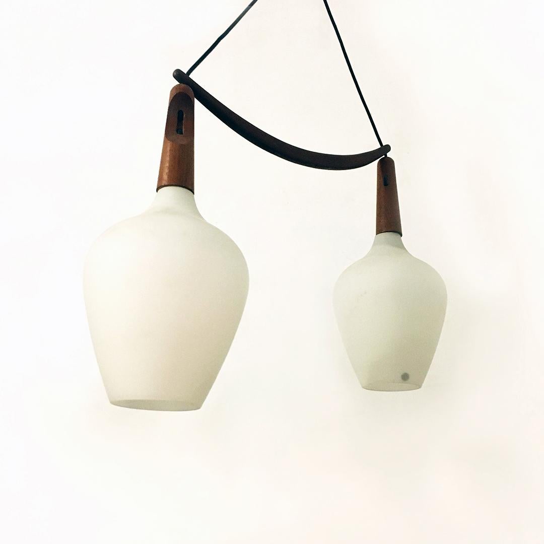 Danish midcentury teak and opaline glass double suspension chandelier, 1960s
Danish double suspension chandelier with central half-moon teak structure that acts as a spacer between the two opaline glasses, of irregular shape and with an external