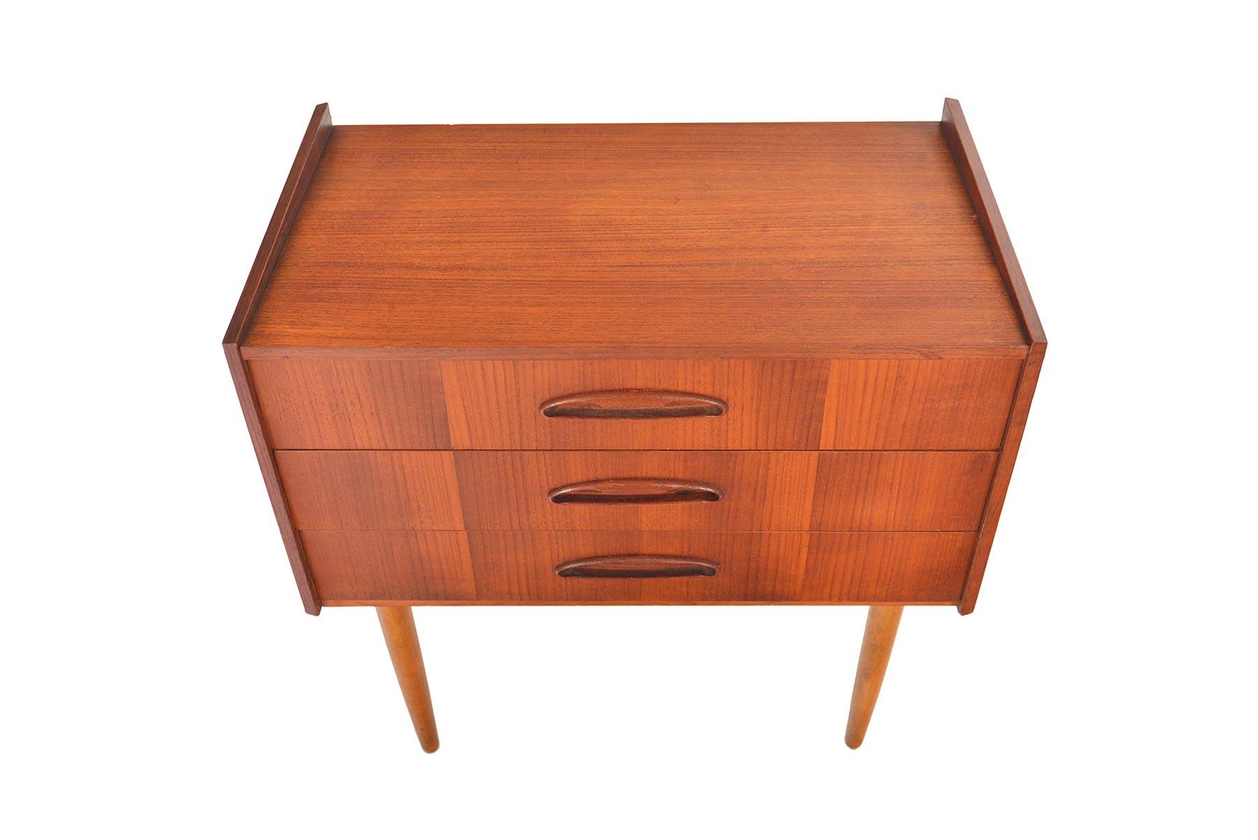 This Danish modern midcentury three drawer chest in teak features gorgeous carved full atomic pulls. Perfect for use in an entry way or as a single nightstand, this piece offers exceptional storage! In excellent original condition with typical wear