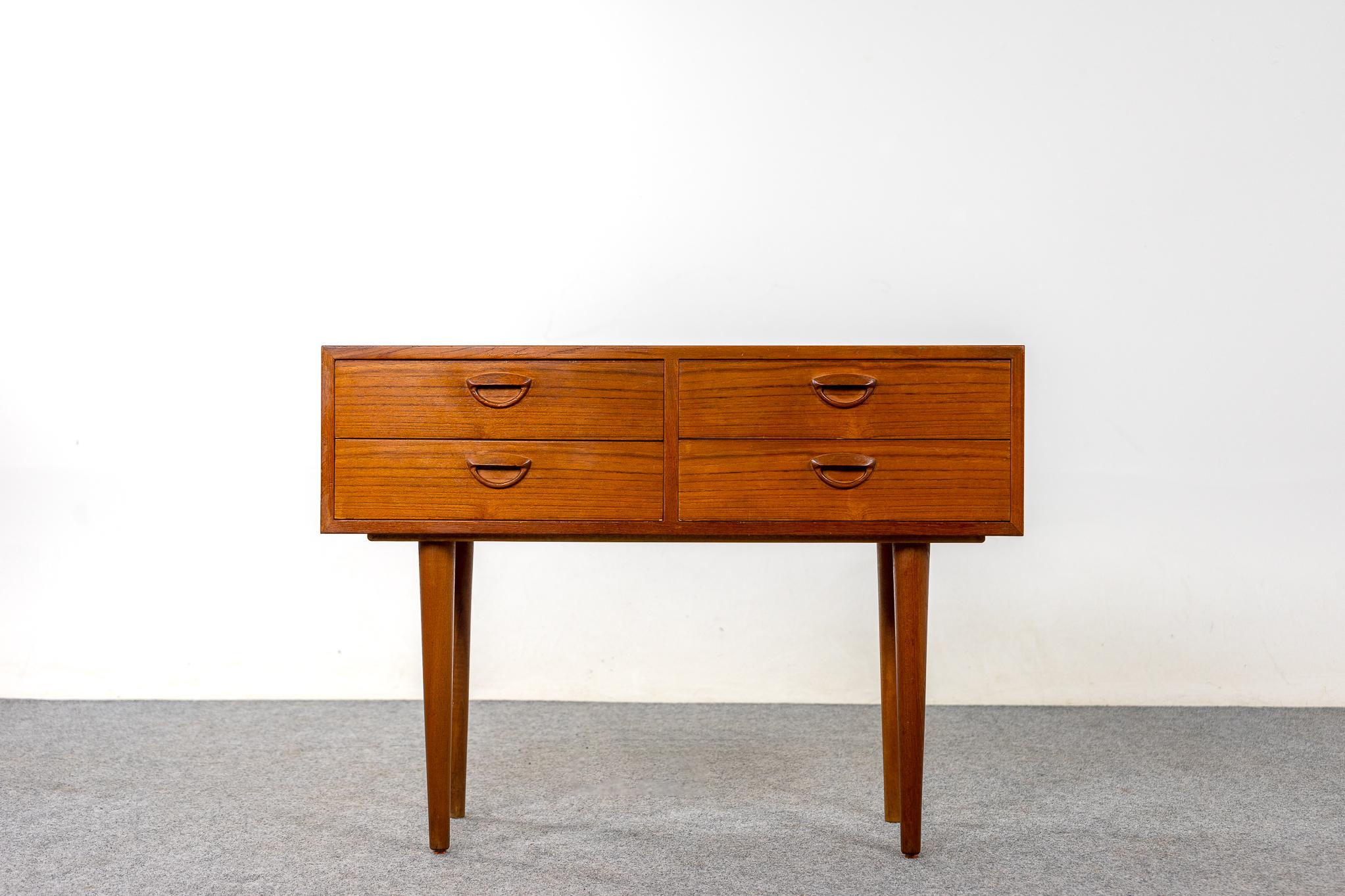Teak mid century bedside table, circa 1960's. Beautifully veneered case rests on slender, tapered, removable legs. Four dovetailed drawers offer storage for small items.

Unrestored item, some marks consistent with age.