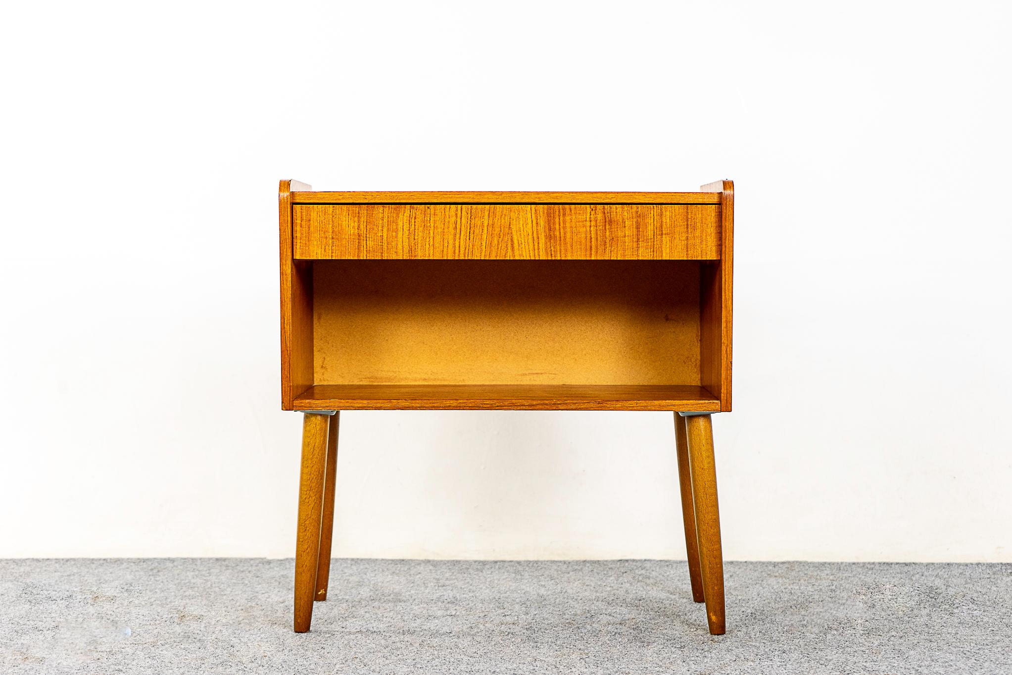 Teak Danish modern bedside table, circa 1960s. Dovetailed drawer offer storage for small items, cubby is perfect for your favorite book! Beautifully veneered case rests on slender, tapered, removable legs.

Unrestored item, some marks consistent