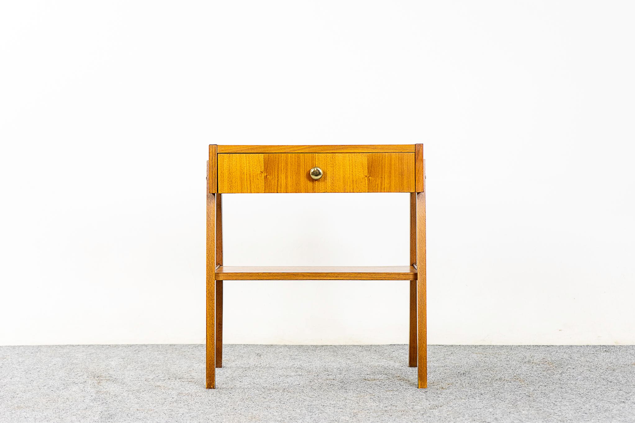 Teak midcentury bedside table, circa 1960s. Beautifully veneered case rests on slender, tapered legs. Single dovetailed drawer offer storage for small items while lower shelf is perfect for your favorite book.

Unrestored item, some very minor marks
