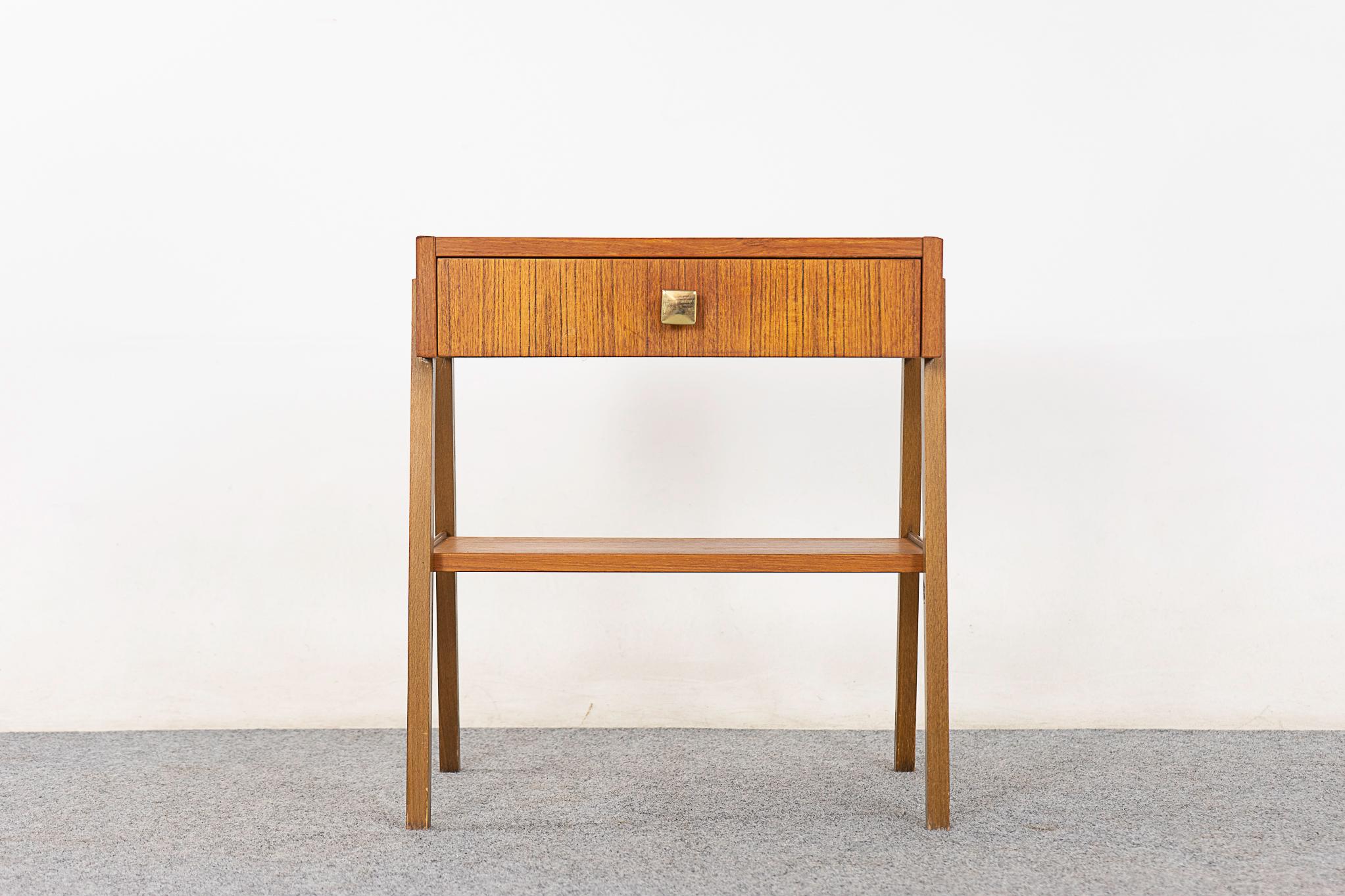 Teak Danish bedside table, circa 1960's. Eye catching scissor legs, sleek drawer and a handy shelf. Veneered case and drawer face with lovely grain patterning.

Please inquire for remote and international shipping rates.