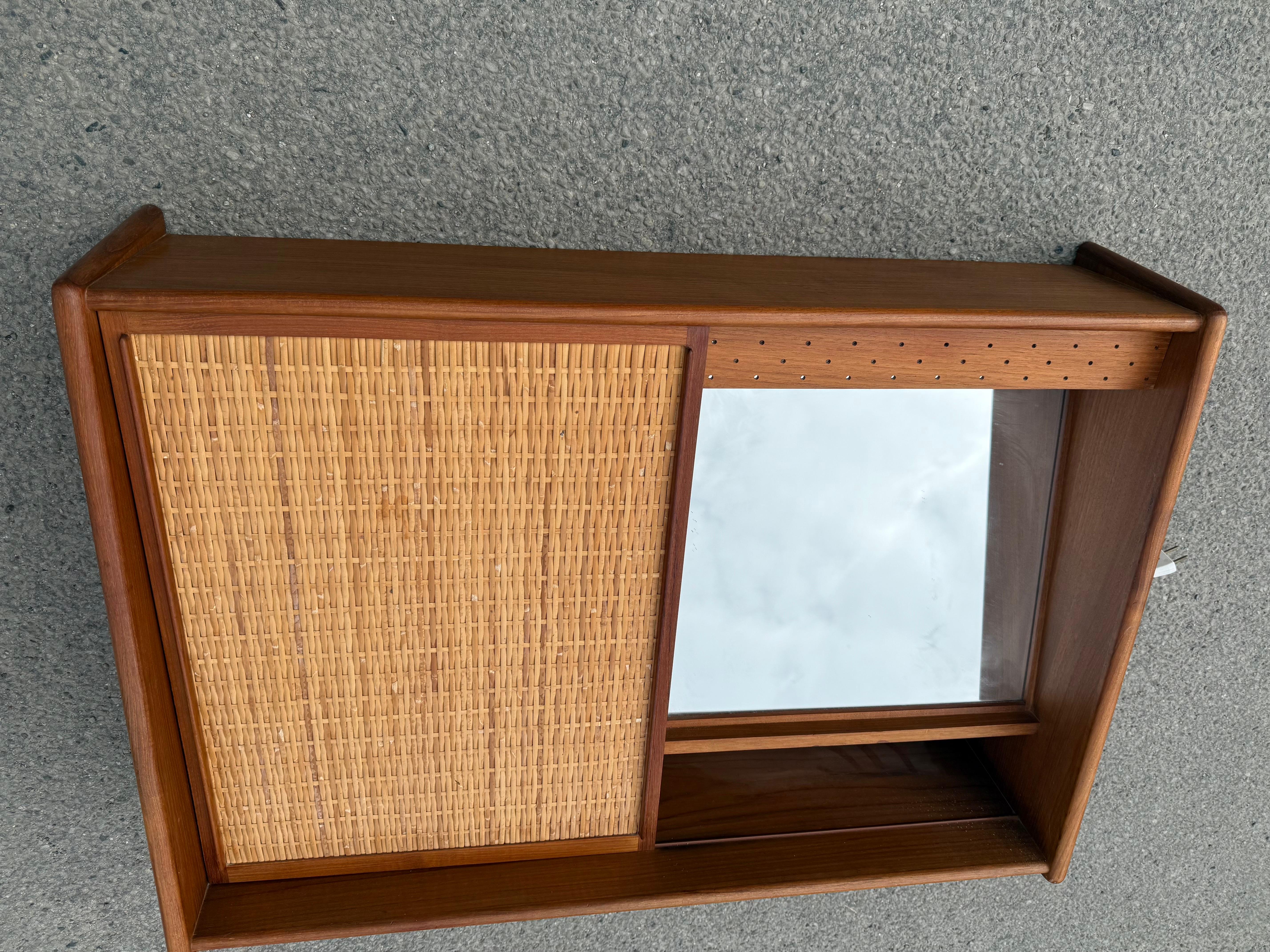Mobiletto da parete in teak e canna danese, anni '60

Bellissimo e pratico armadio a muro danese Mid-Century Modern, realizzato alla fine degli anni '50 o '60. Classico design scandinavo con linee pulite, una calda struttura in teak e un'anta