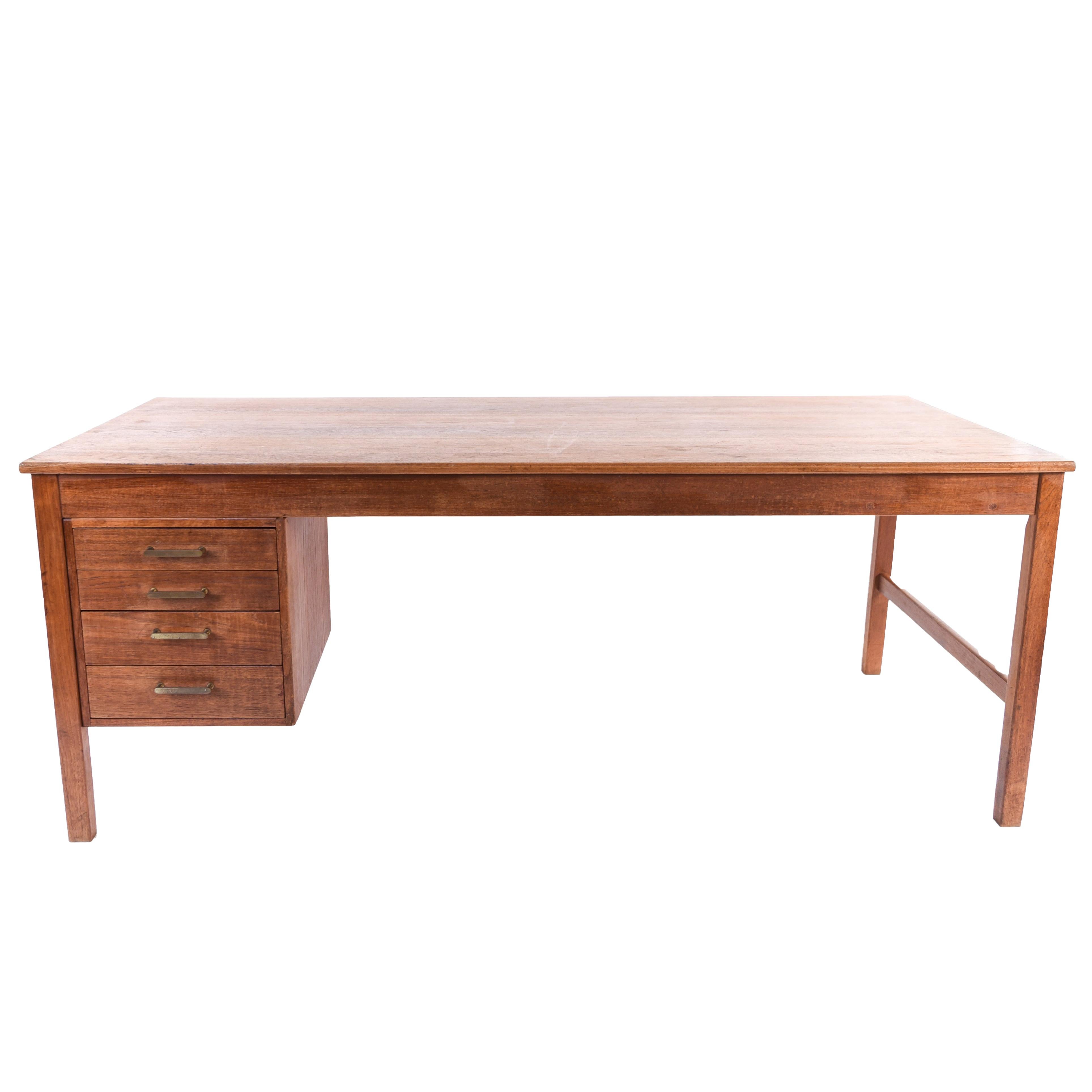 This Danish midcentury teak desk has a sleek modern design with thin legs and writing surface. Drawers with brass handles provide storage to the otherwise minimal piece.